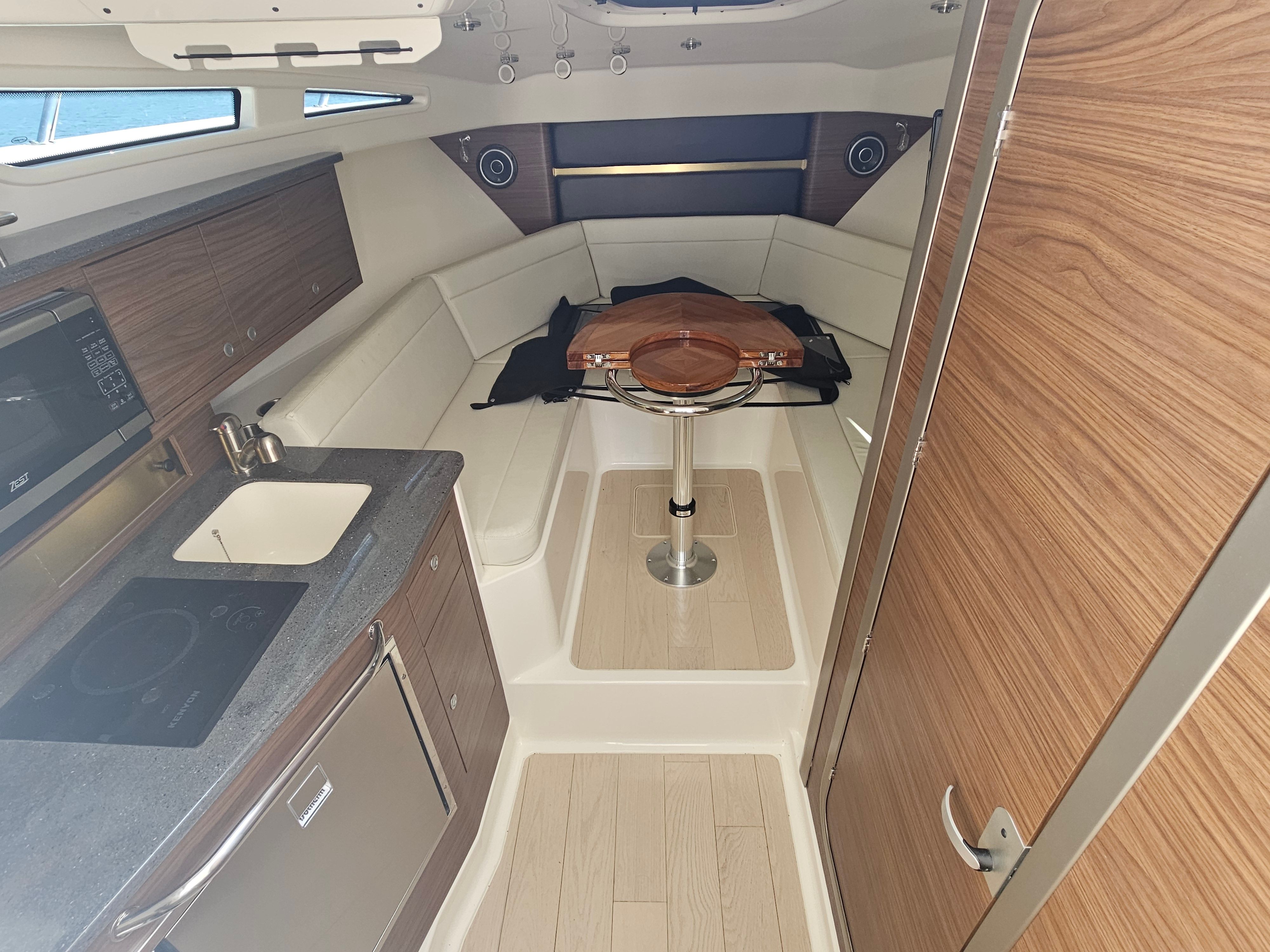 Interior of a modern yacht with wood accents, kitchenette, and seating area.