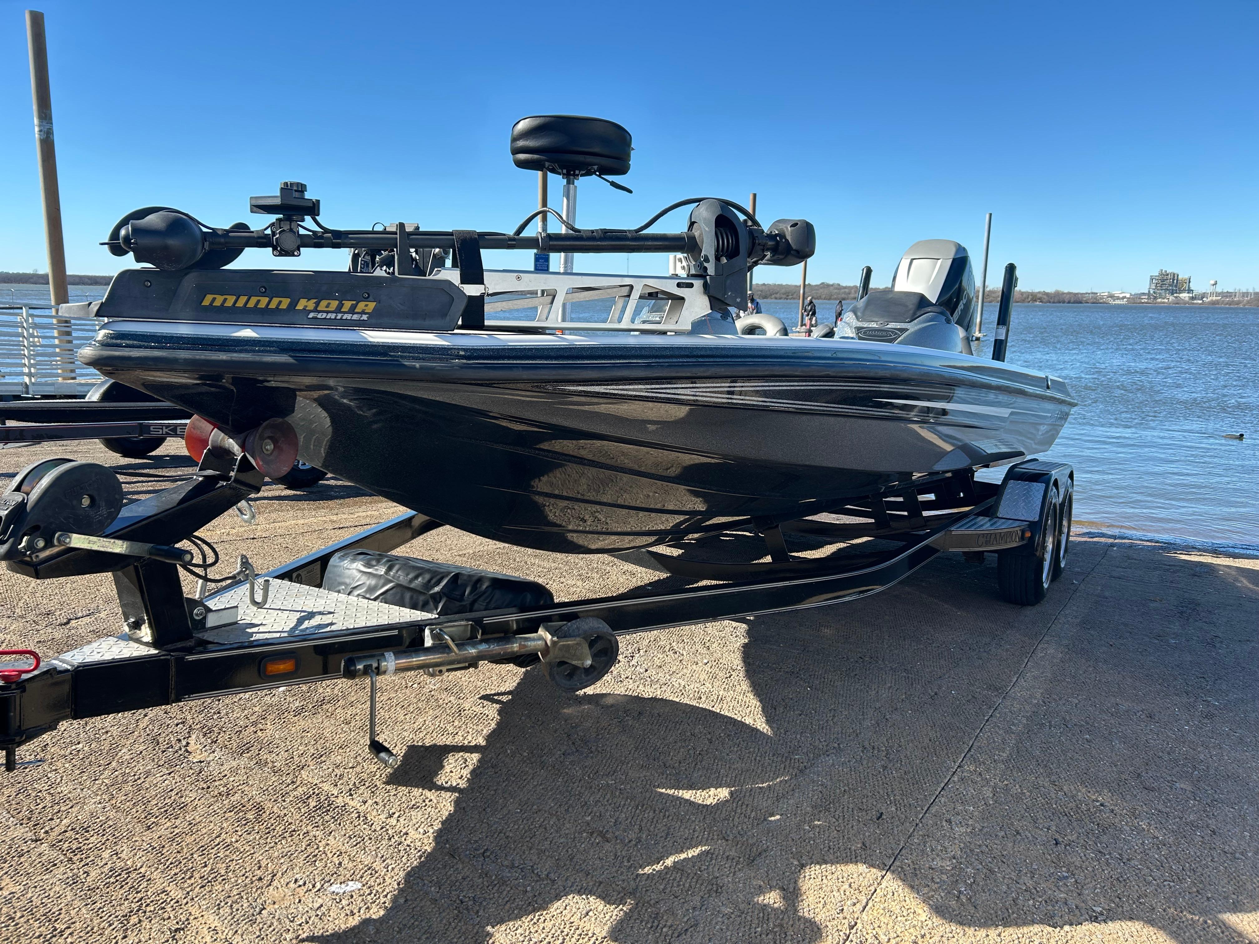2009 Champion 210 Elite boat on trailer by the water, featuring Minn Kota equipment.