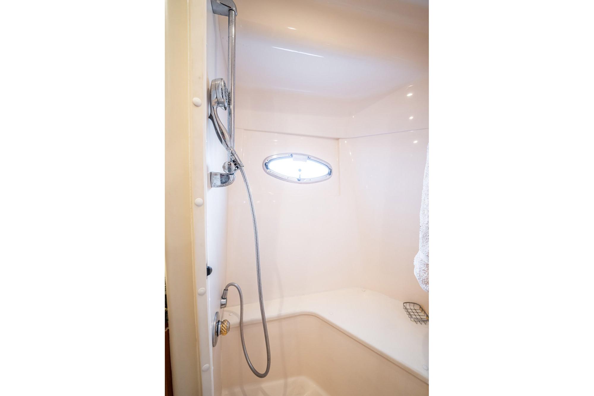 Shower area in 2005 Carver 56 Voyager yacht with chrome fixtures and small window.