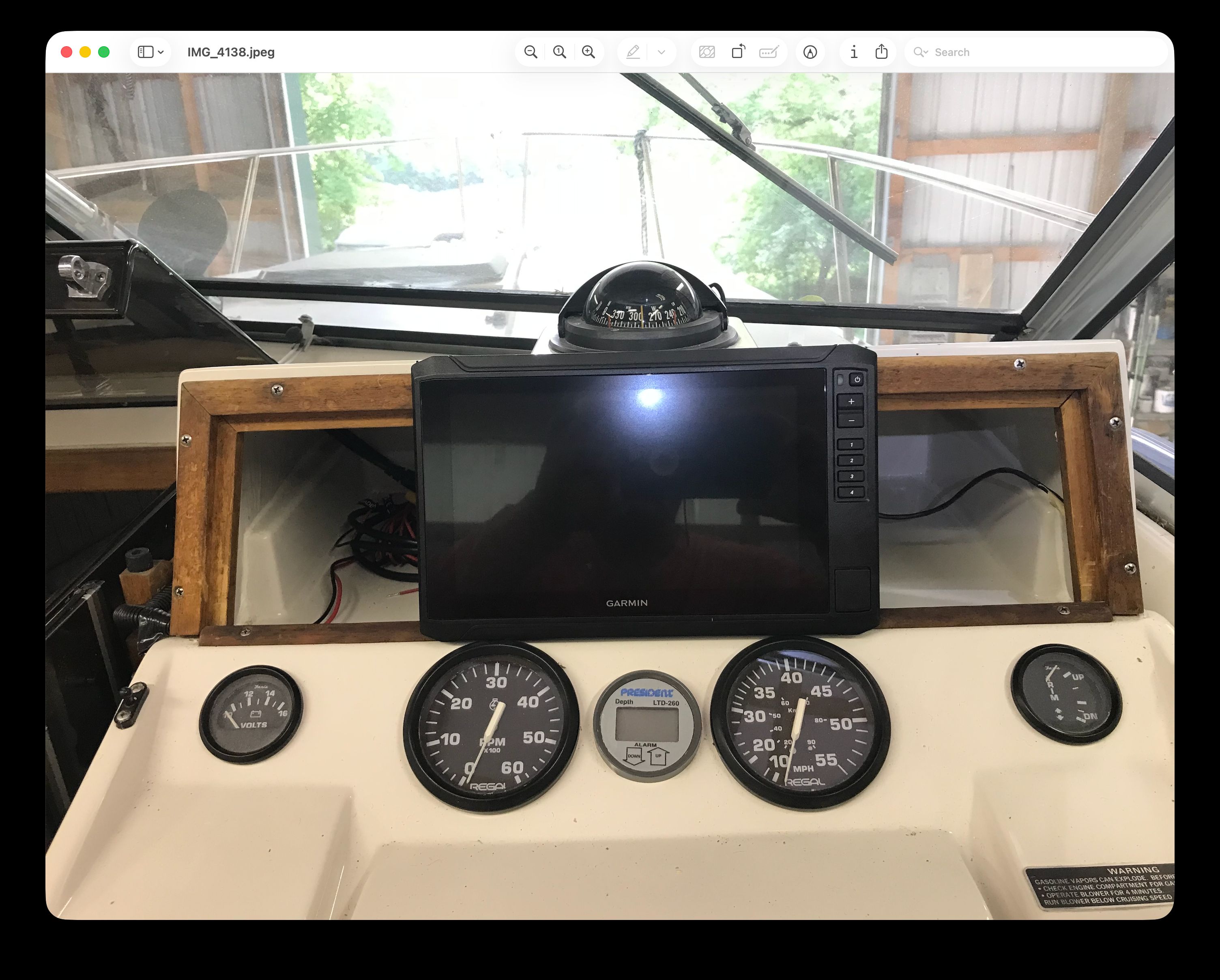 The dashboard of a boat with a Garmin screen and several gauges.