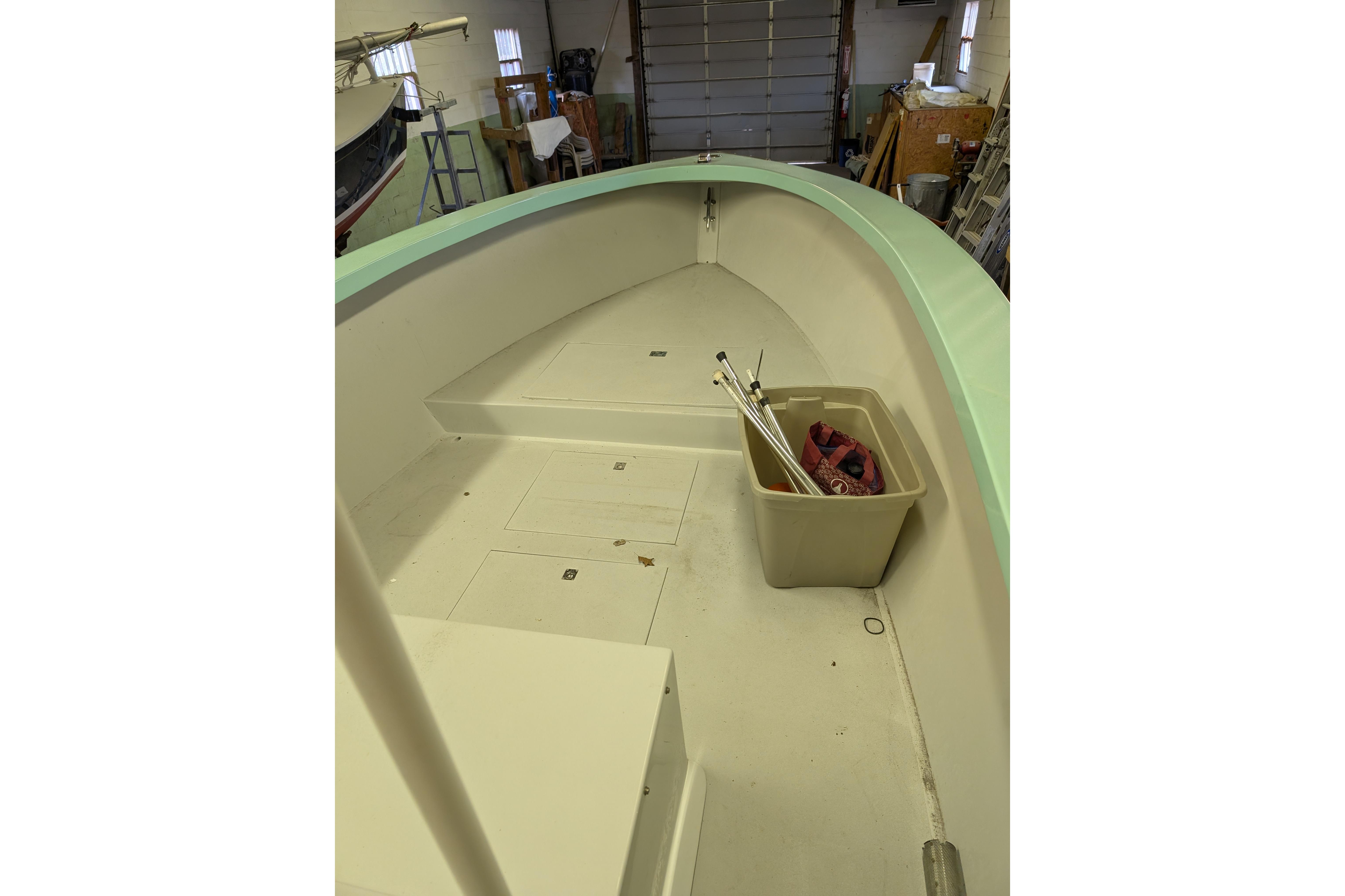 1963 Rybovich 22 boat interior with storage bin and equipment in a workshop setting.