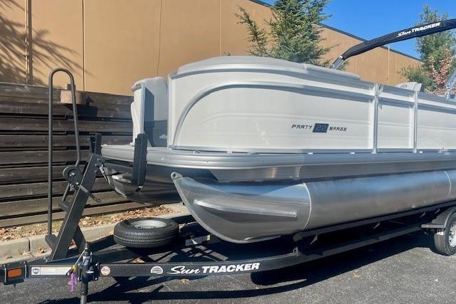 2026 Sun Tracker Party Barge 22 RF DLX pontoon boat on trailer, parked outdoors.