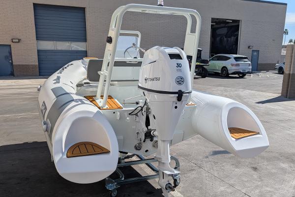2025 Tide Craft San Juan 11 inflatable boat with Tohatsu outboard motor in a garage setting.