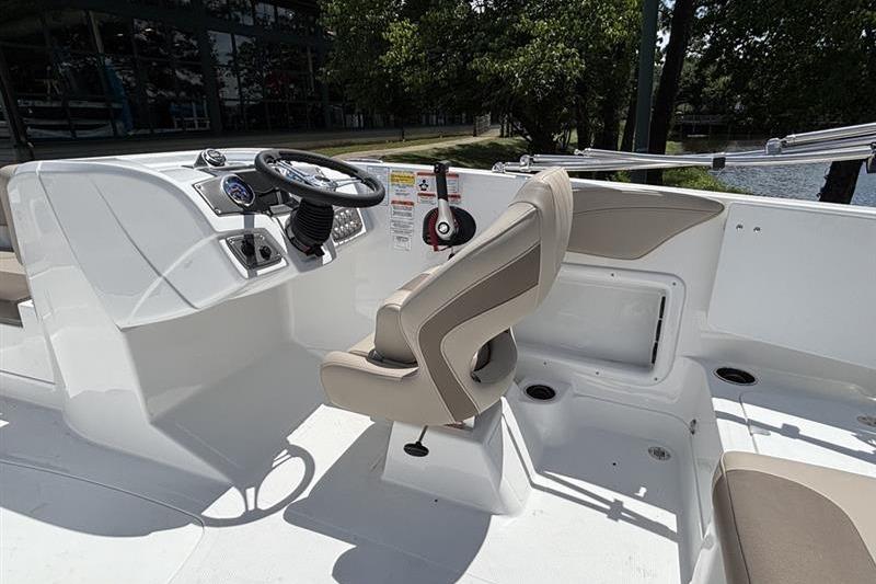 2026 Tahoe 2150 boat interior with steering wheel and seating, near a serene water body.