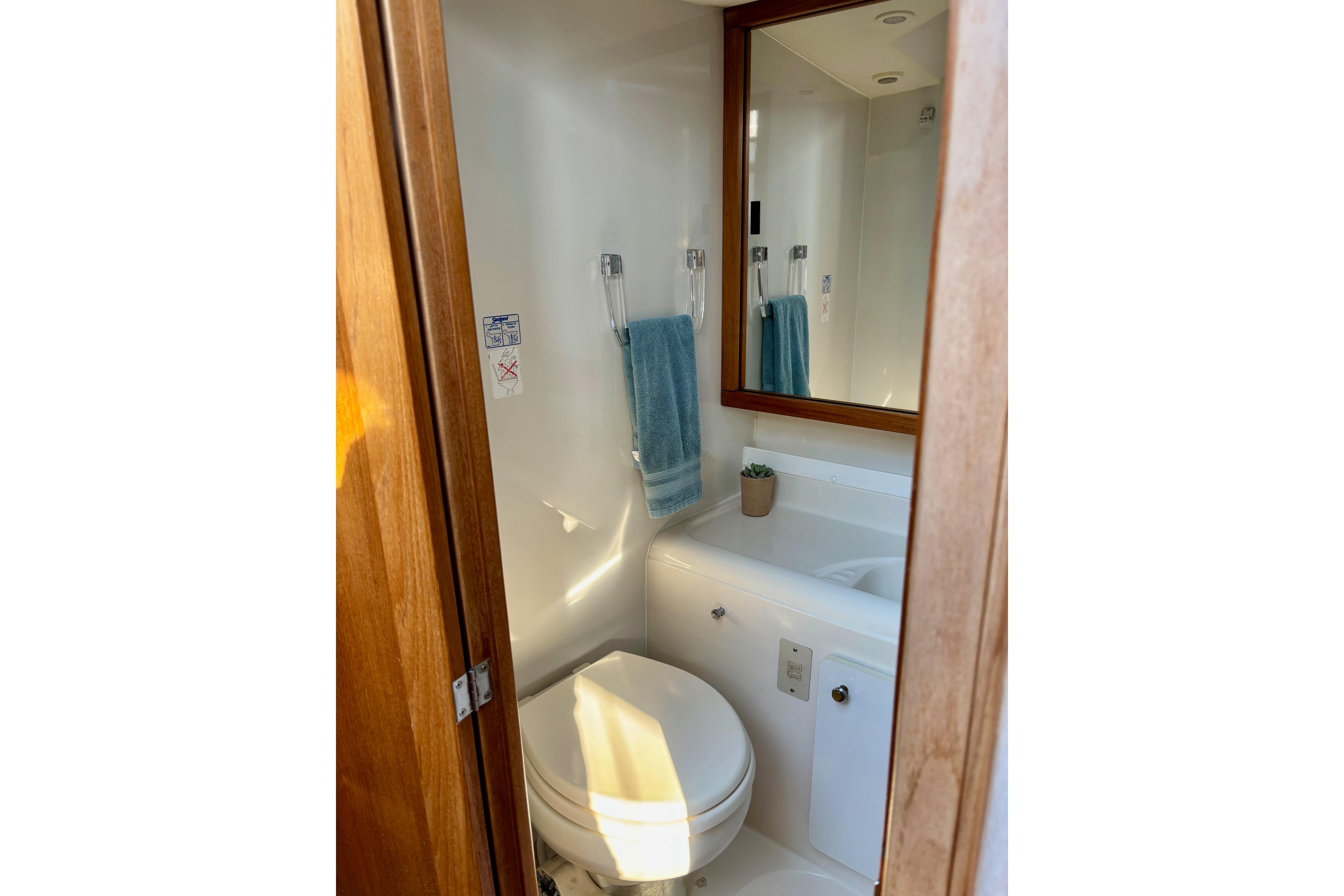 Bathroom interior of 1998 Bayliner 3388 Command Bridge Motoryacht with mirror and towel.