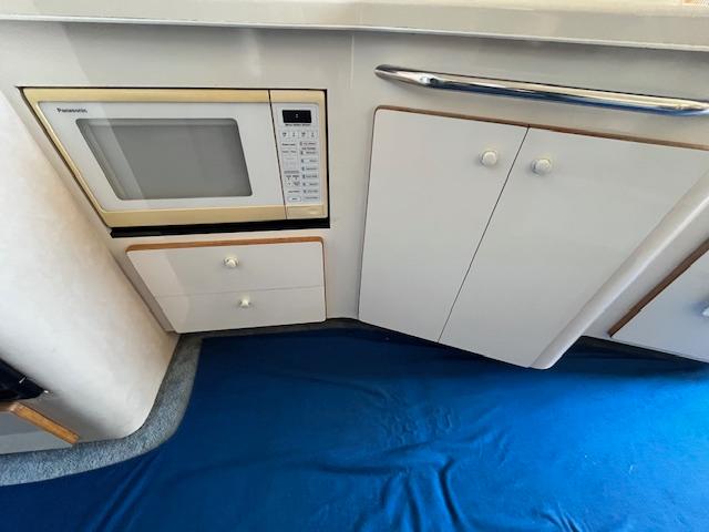 Interior of 1995 Sea Ray 440 Express Bridge with microwave and cabinetry.