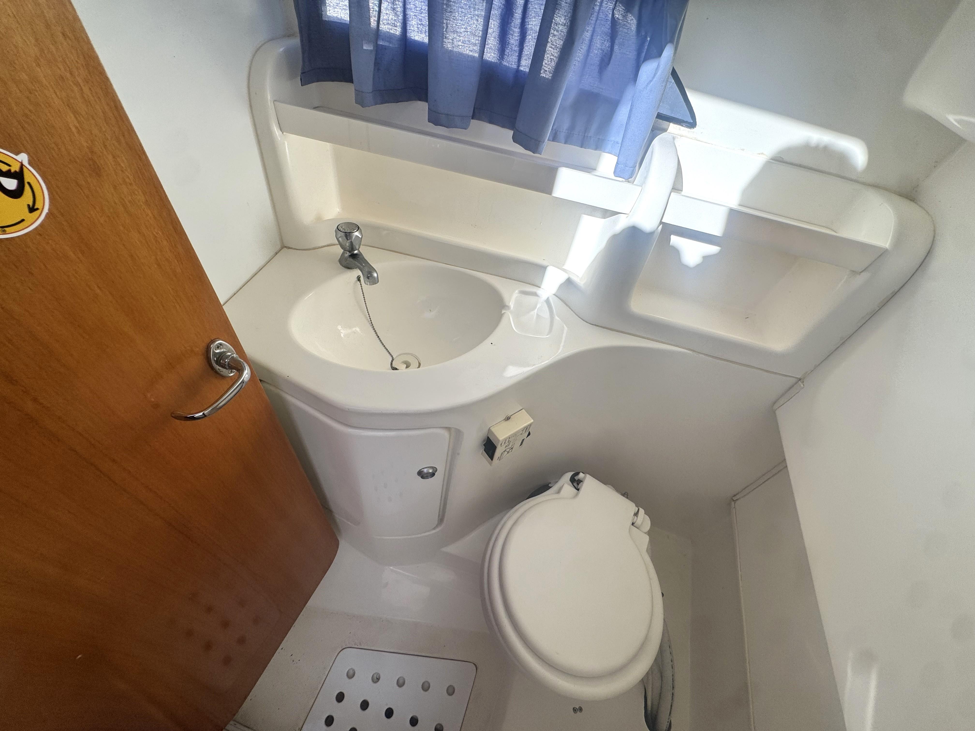 Compact bathroom in 2002 RIO 800 Cabin Fish boat with sink and toilet.