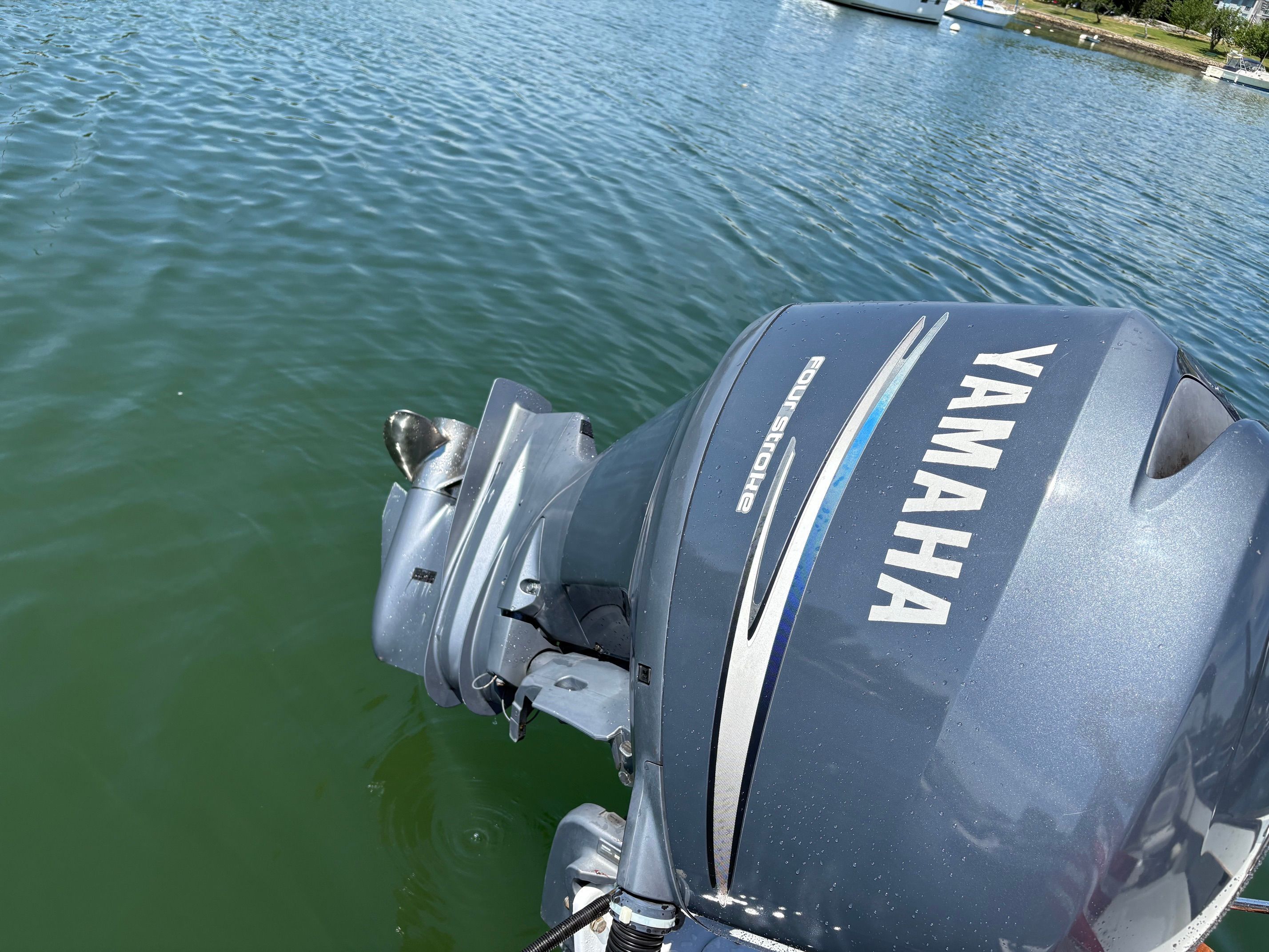 A Yamaha outboard motor on a boat in the water, with another boat in the background.