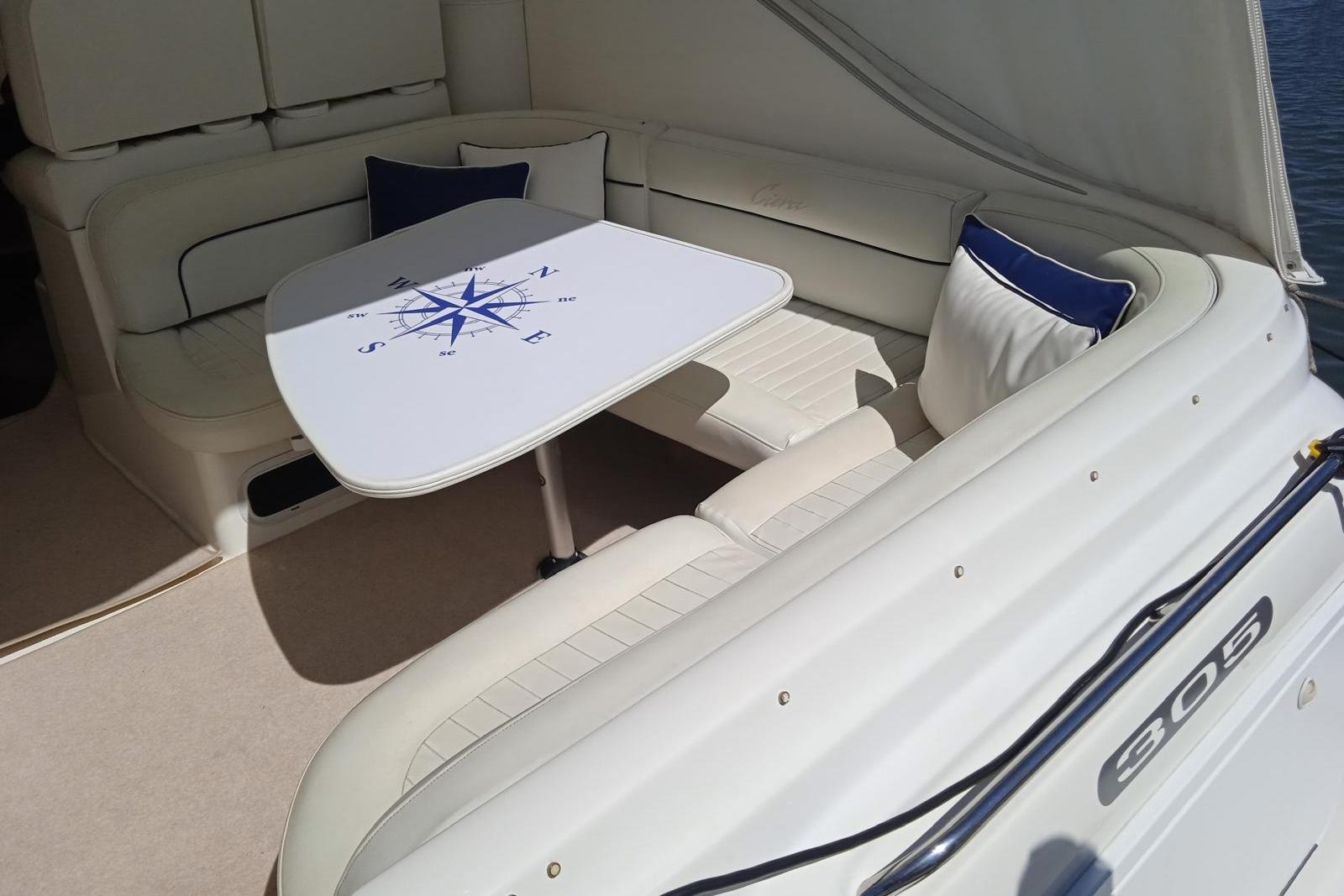 2004 Bayliner 3055 Ciera boat interior with compass-themed table and cushioned seating.