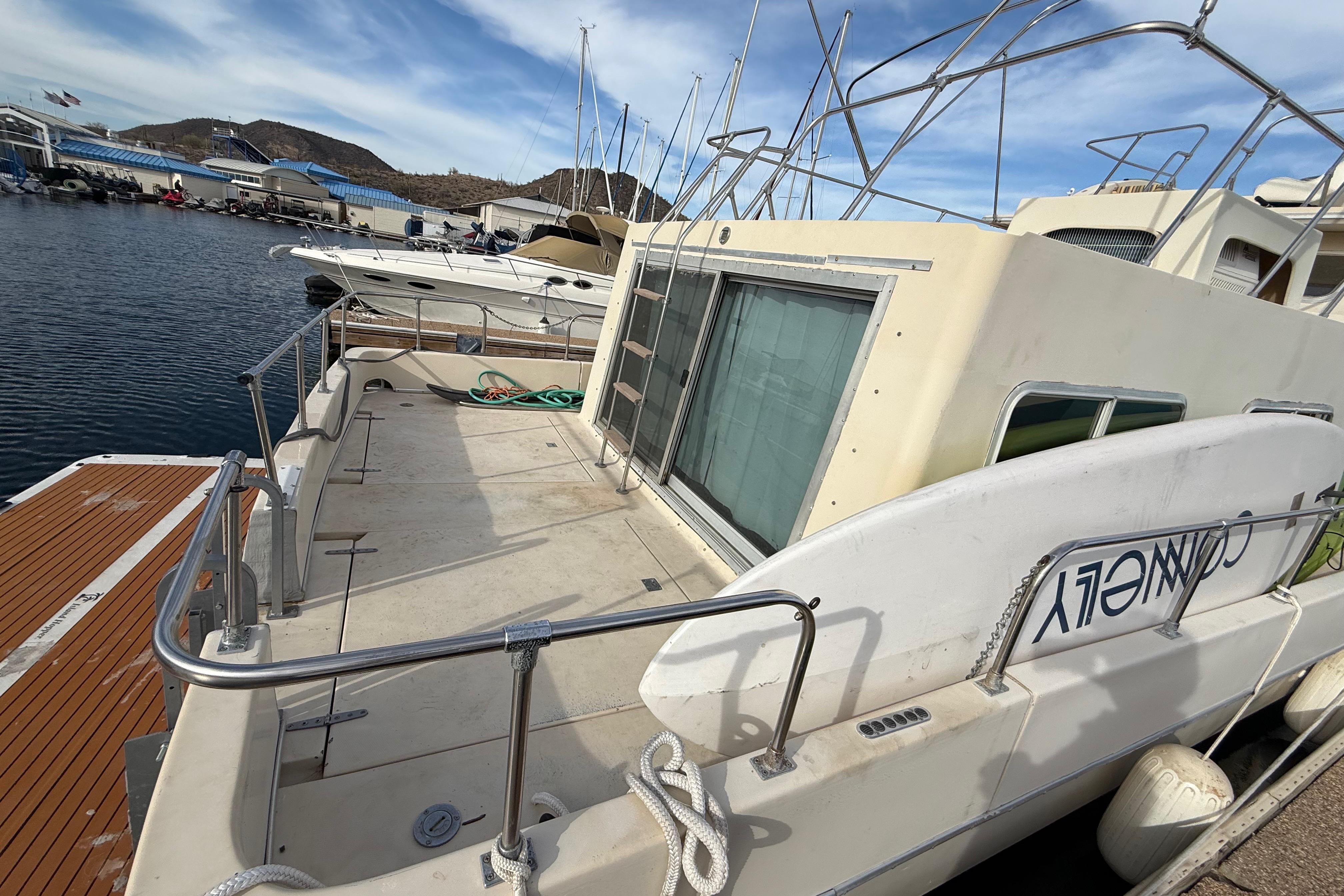 1983 Holiday Mansion 37 Barracuda houseboat docked at marina, featuring spacious deck and railing.