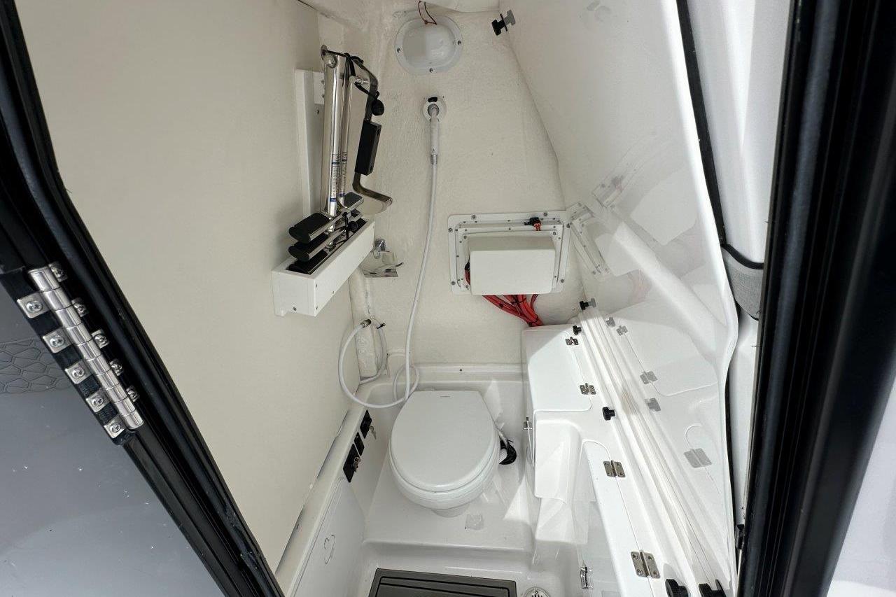 2026 Tidewater 272 LXF boat interior with compact marine toilet and storage.