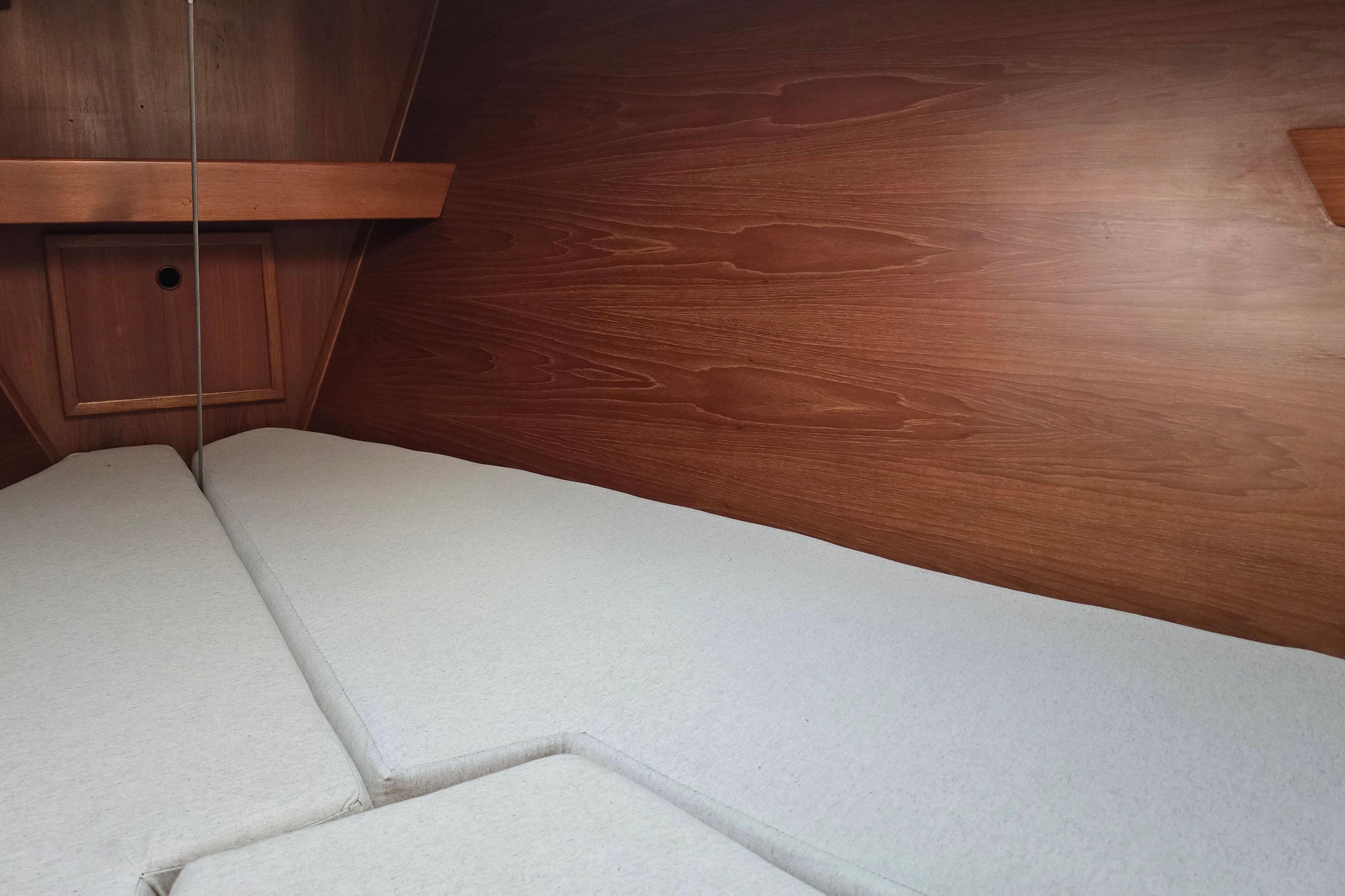 Interior cabin of a 1987 Breehorn 37 sailboat with wooden paneling and cushioned berth.