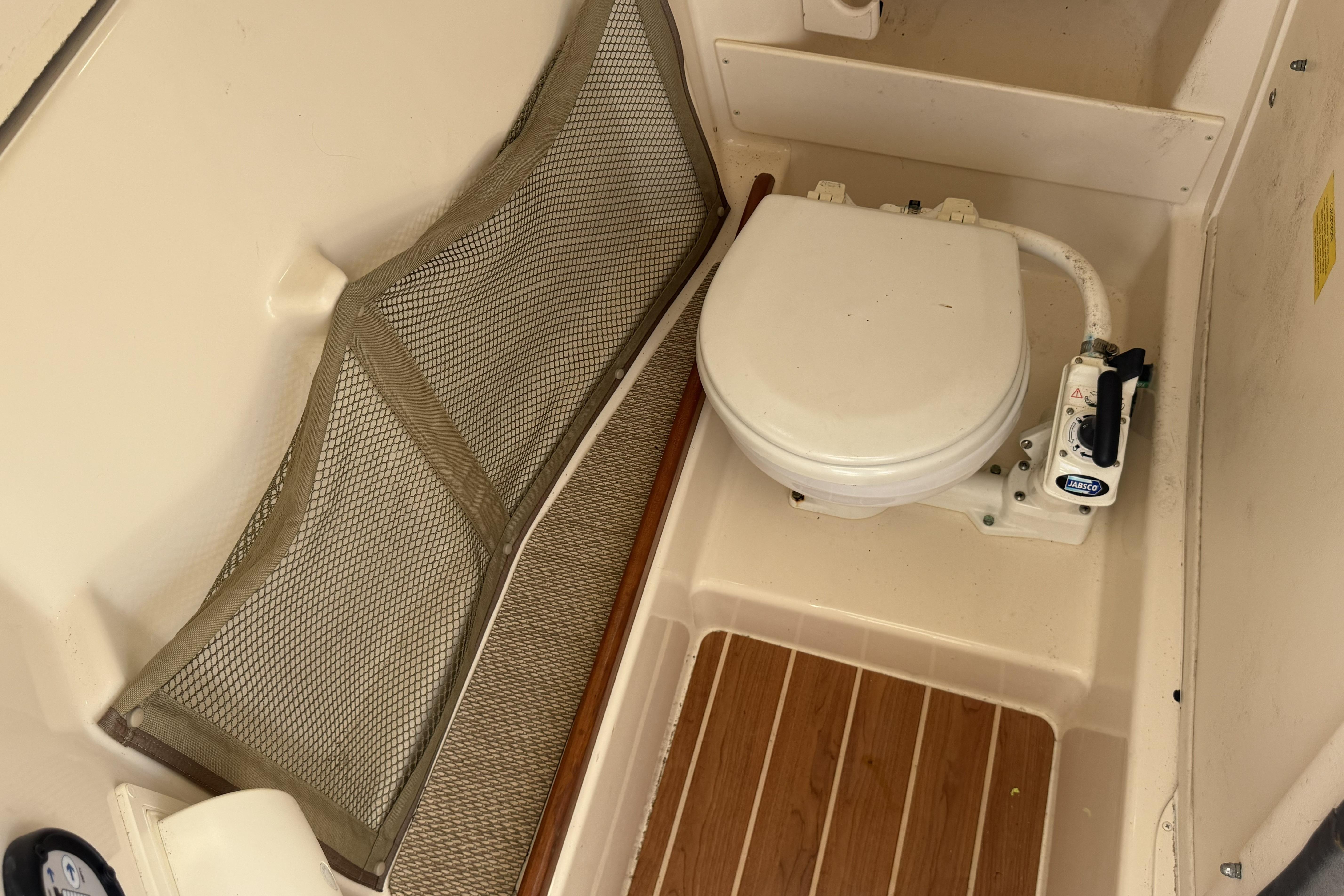 2014 Grady-White Freedom 275 boat toilet with wooden flooring and storage net.