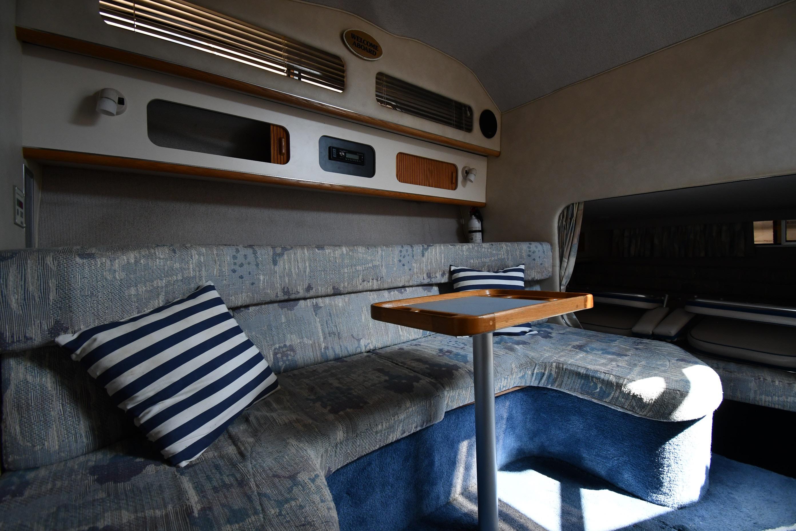 Interior of 1993 Sea Ray 300 Sundancer with cozy seating and striped pillows.
