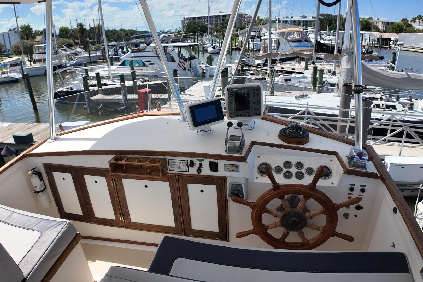 1978 Grand Banks 42 Classic yacht helm with wooden wheel and navigation instruments at marina.