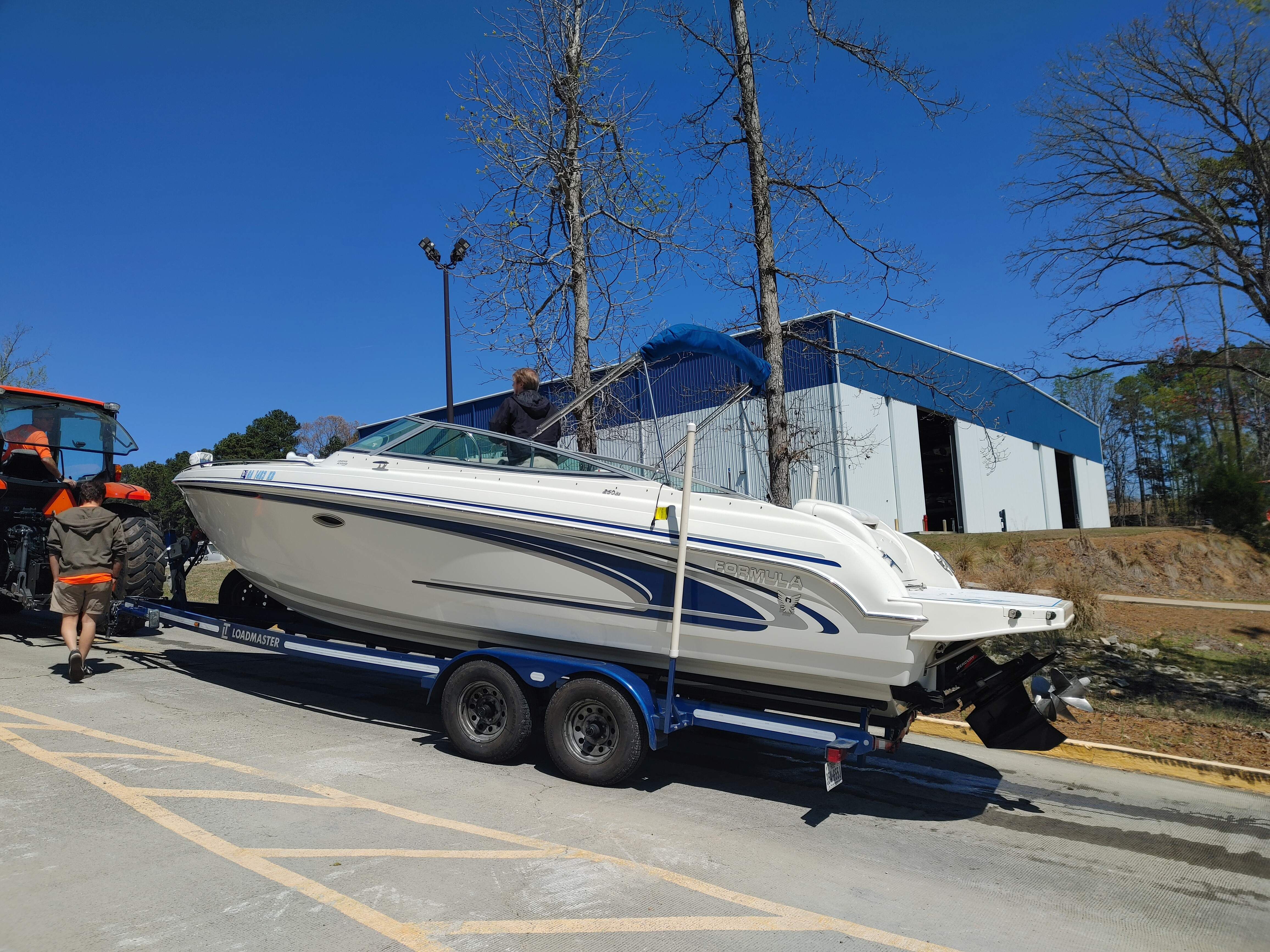 A white motorboat on a trailer, featuring blue accents and a blue canopy.
