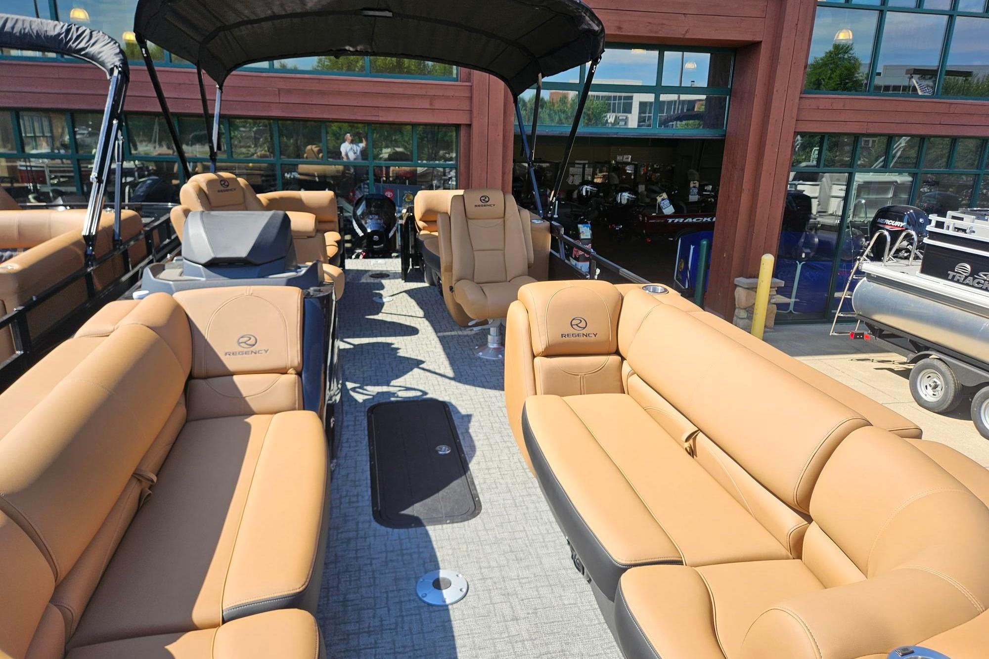 2026 Regency 230 DL pontoon boat with tan seating and canopy, displayed outdoors.