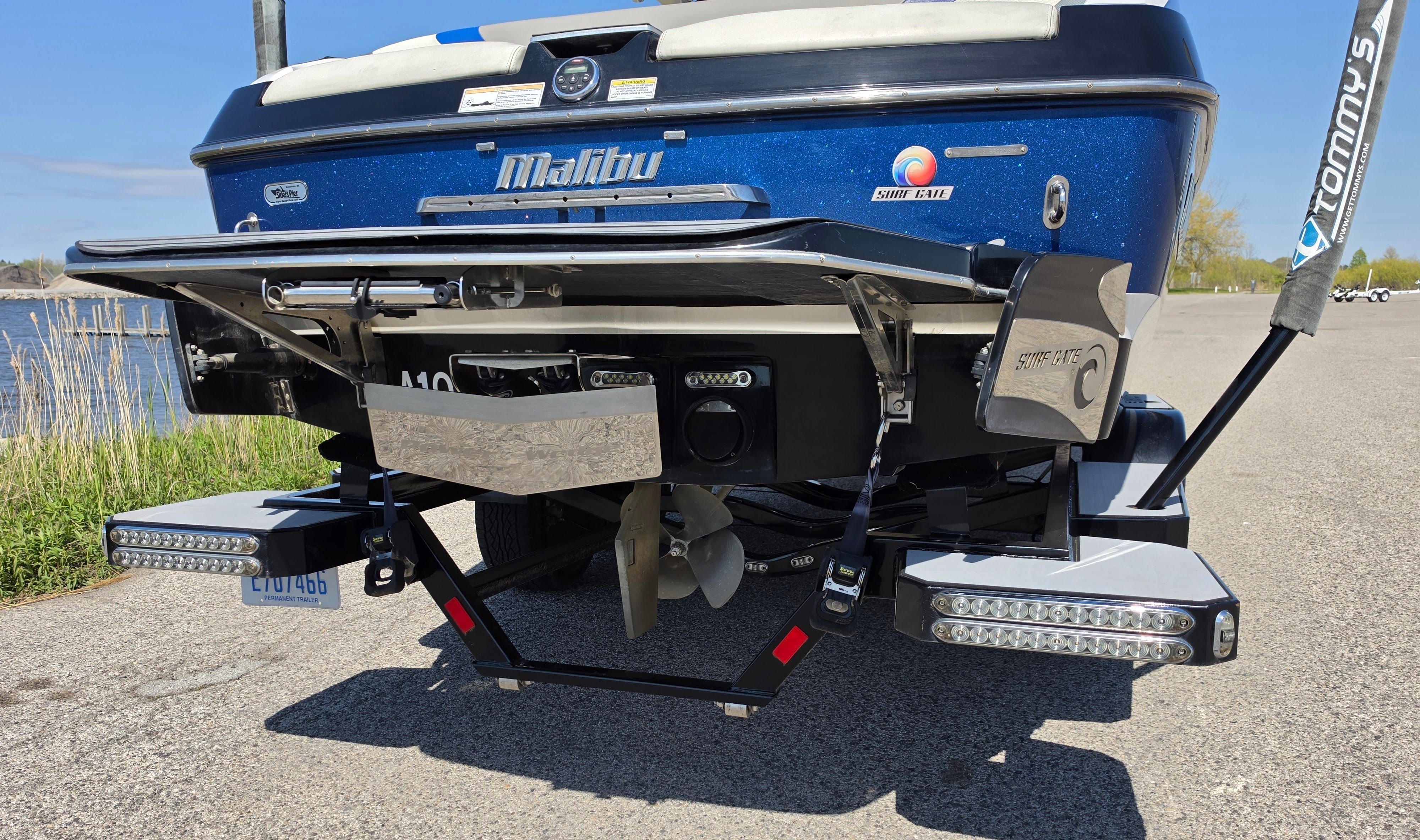 Rear view of a 2014 Malibu Wakesetter 24 MXZ boat by the shore.