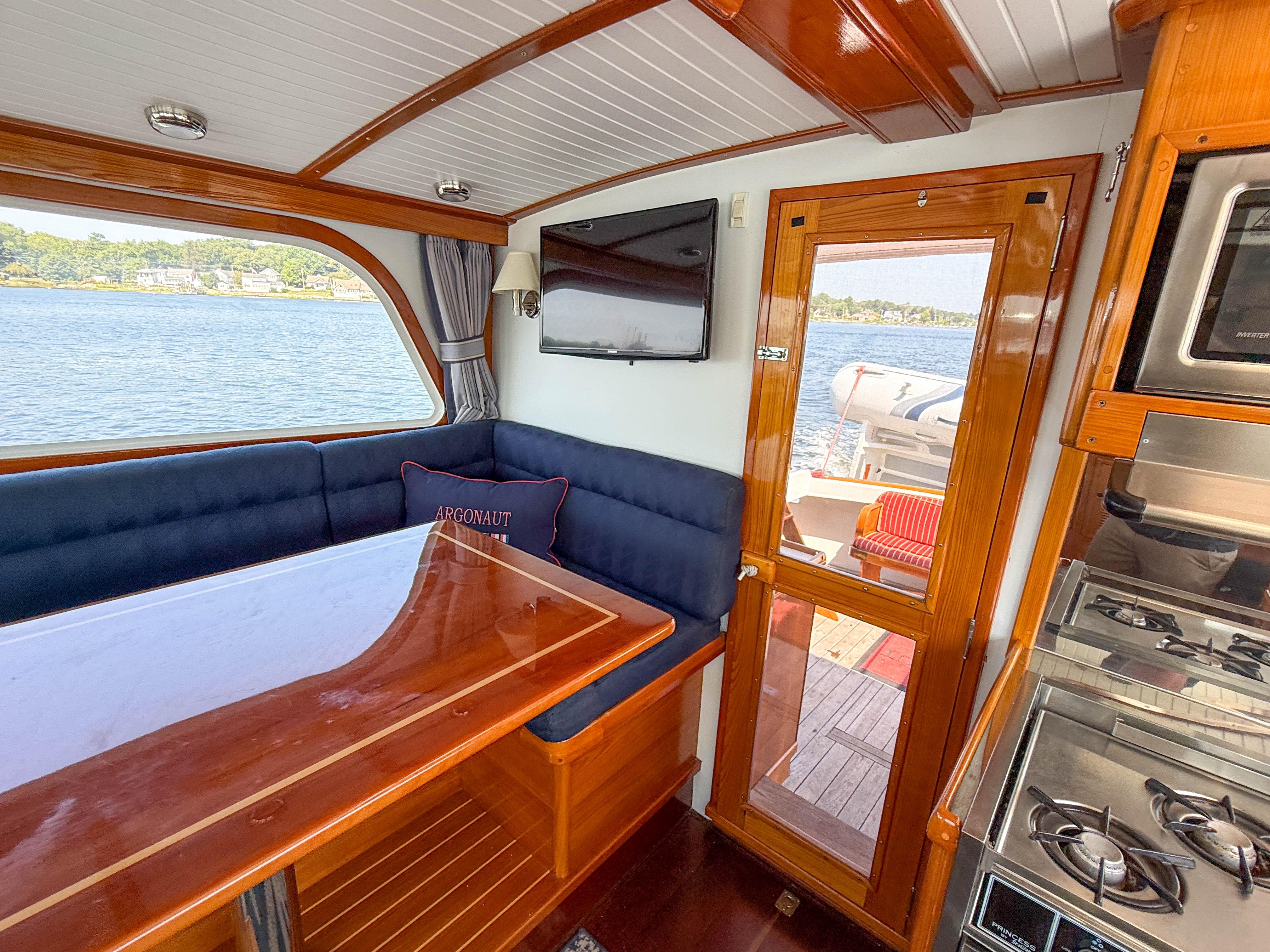 Interior of 1984 Wilbur 38 boat with dining area, stove, and scenic water view.