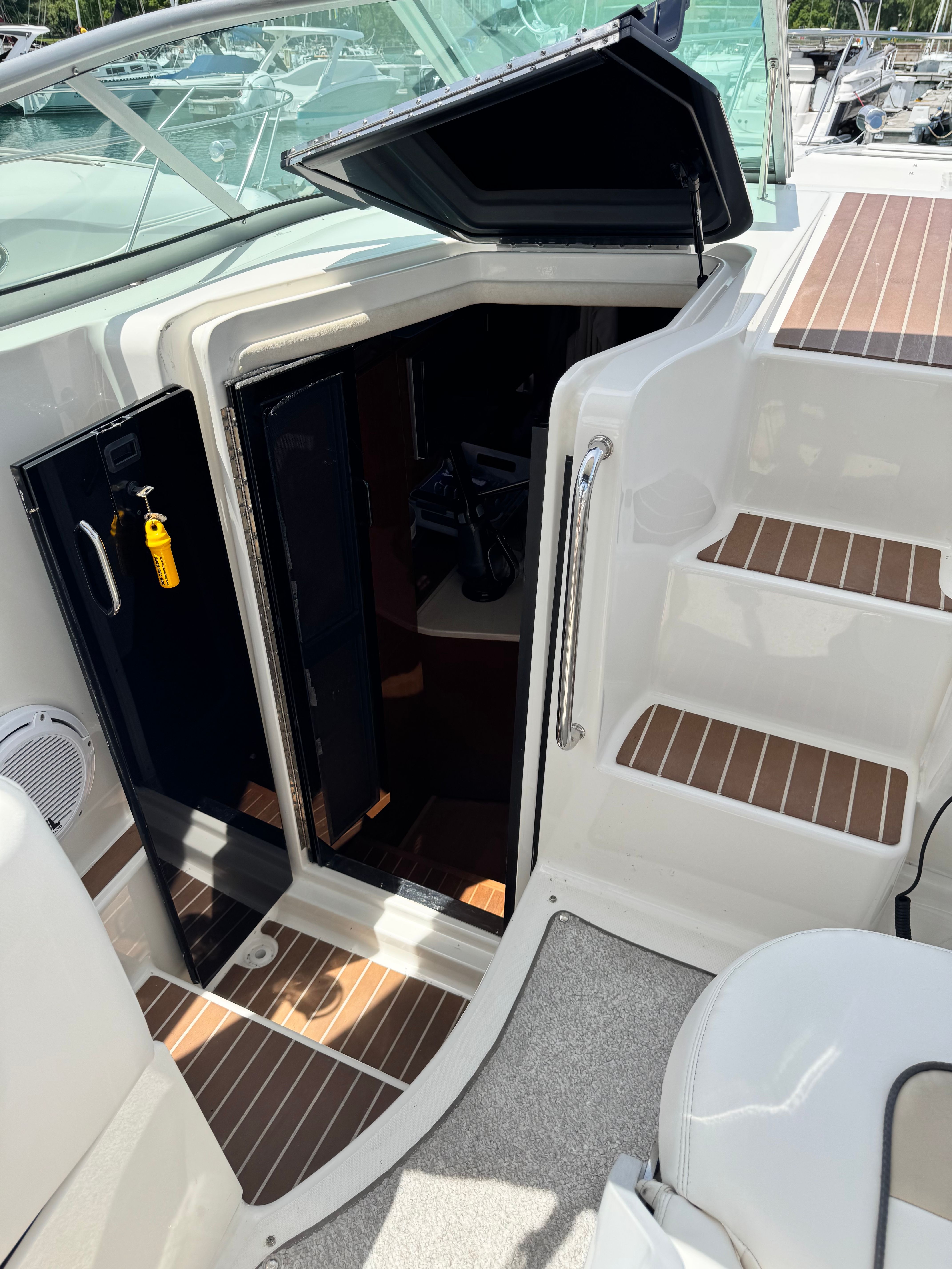 The 2010 Sea Ray Sundancer 310 features an open cabin door with wooden steps and sleek design.