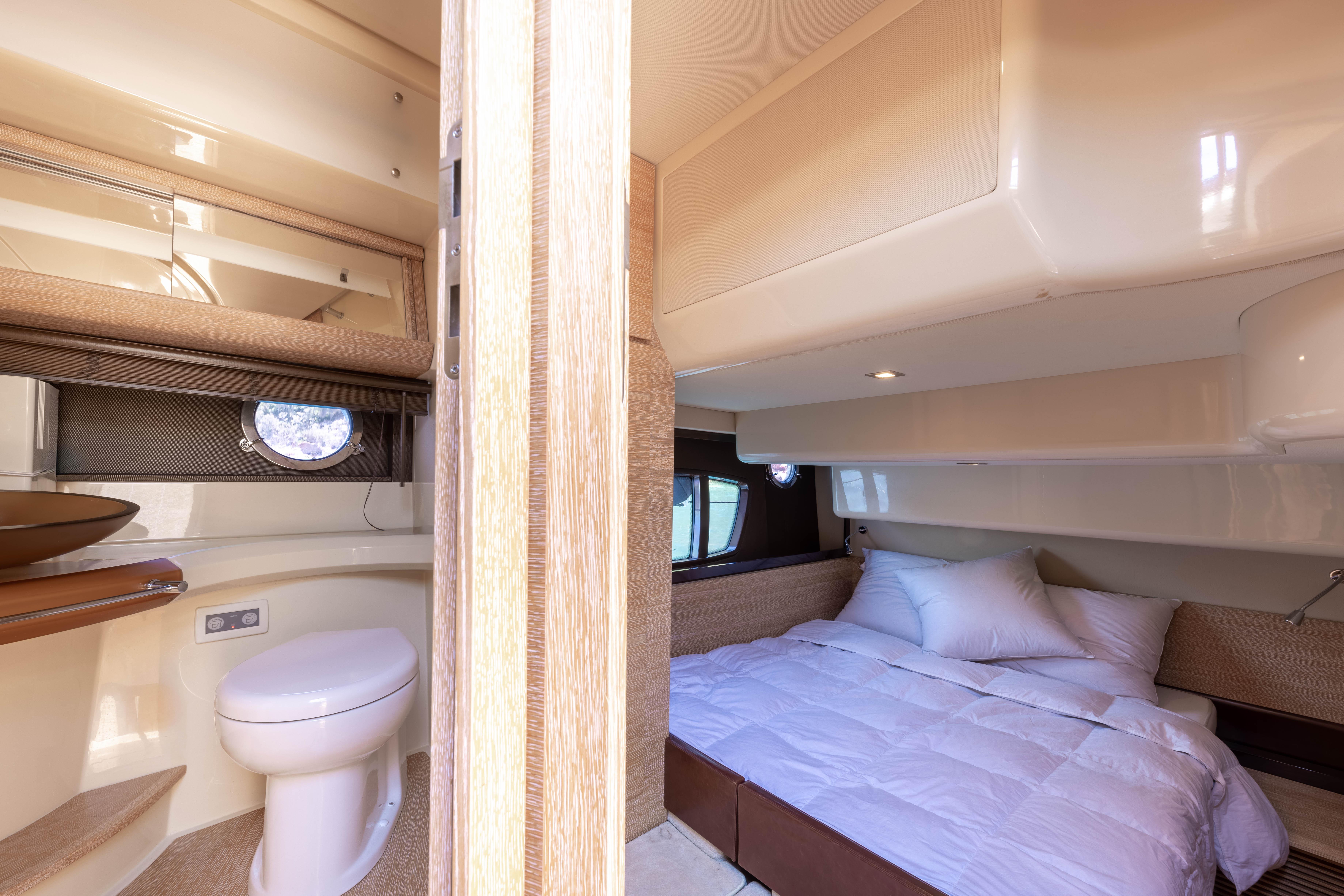Luxurious interior of 2010 Azimut 47 Fly yacht featuring cozy bedroom and modern bathroom.