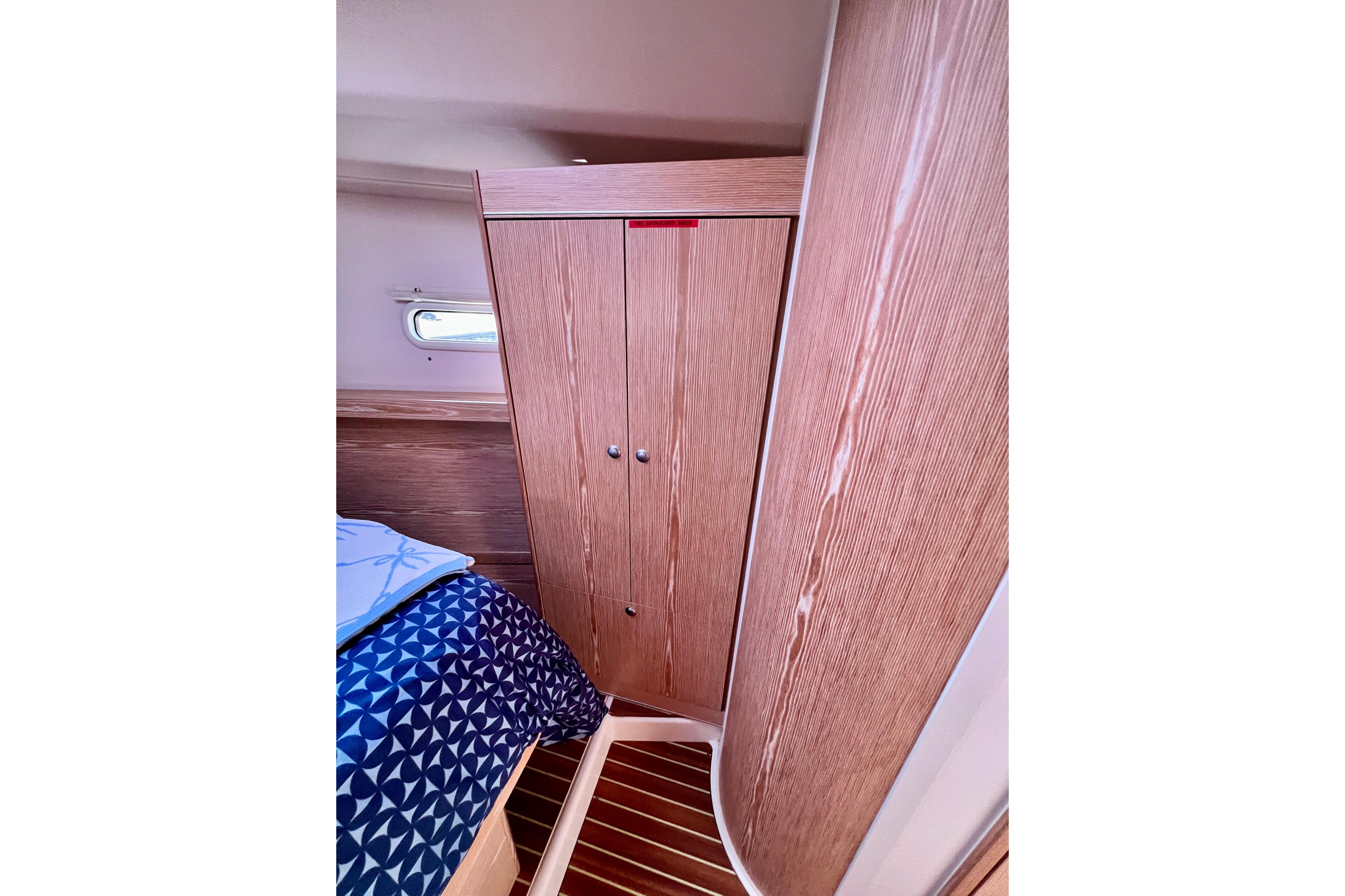 Interior of 2016 Hanse 455 yacht cabin with wooden wardrobe and patterned bedding.