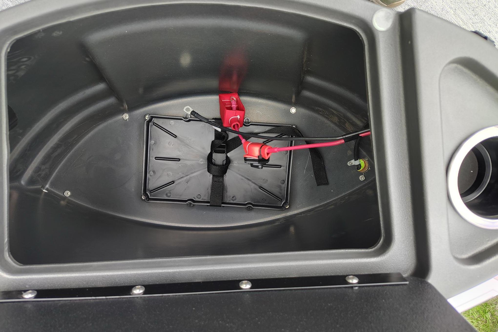 Battery compartment of 2026 Sun Tracker Bass Buggy 18 DLX boat, featuring wiring and secure straps.