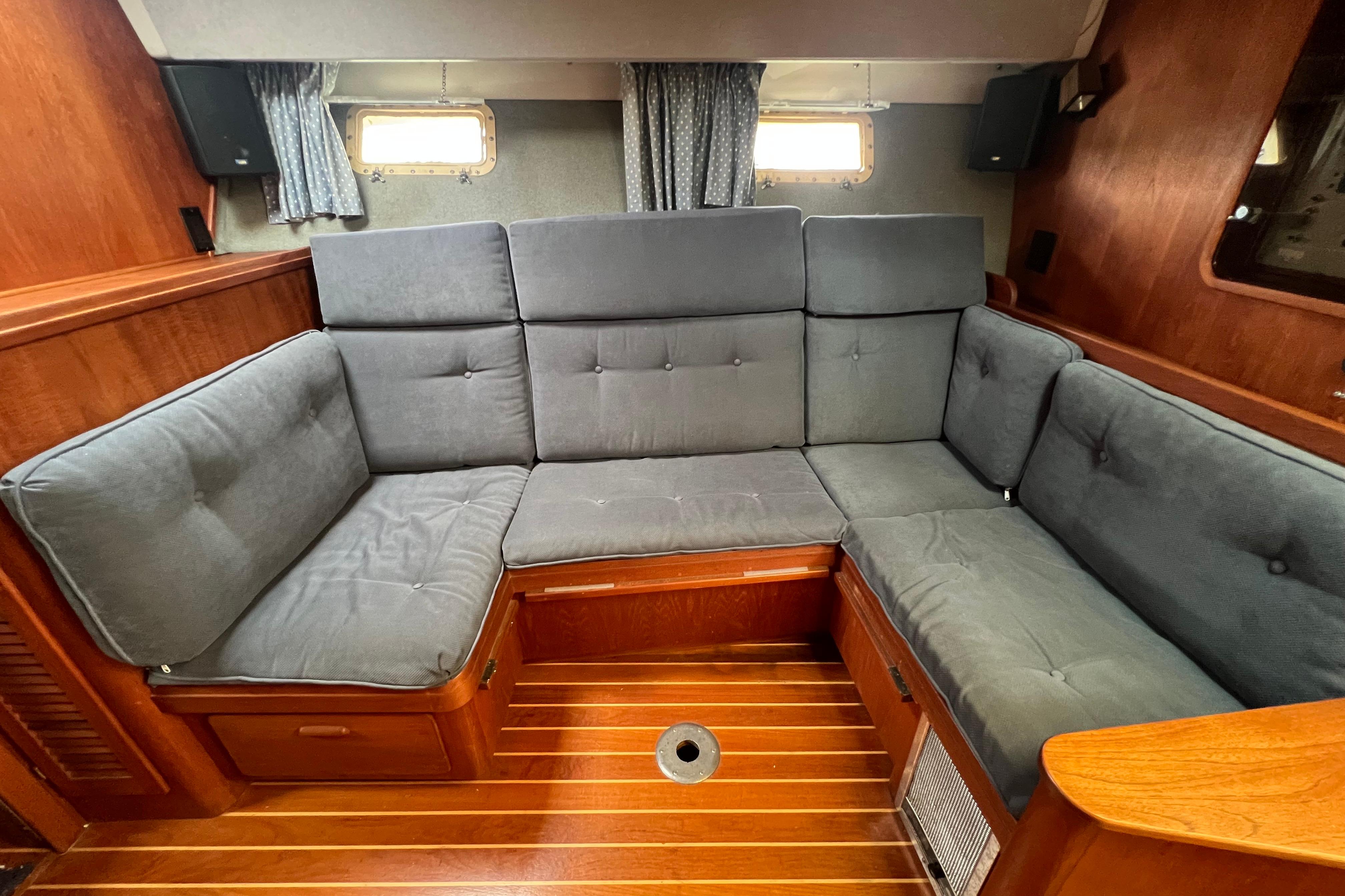 Cozy interior of 1985 Tiara 36 OPEN yacht with gray cushioned seating and wooden flooring.