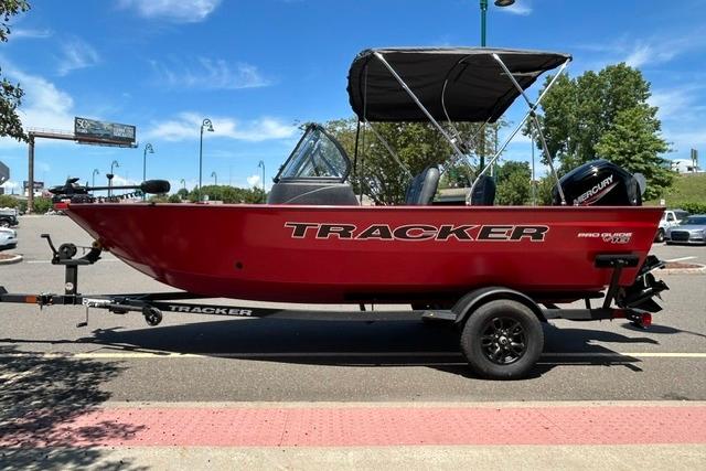 2026 Tracker Pro Guide V-16 WT boat, red, parked on trailer in sunny outdoor setting.