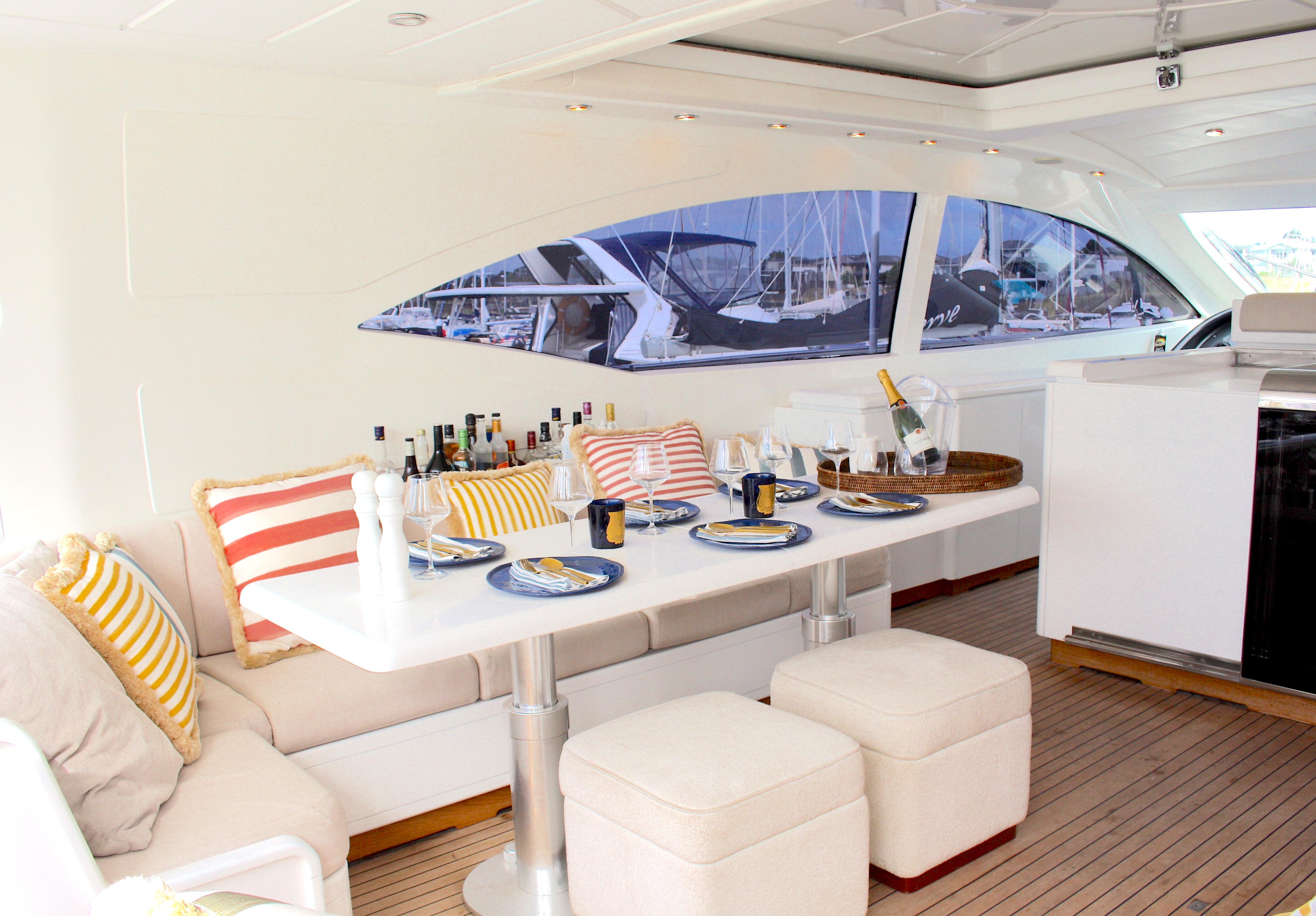 Luxurious 2002 Mangusta 72 yacht interior with elegant dining setup and striped cushions.