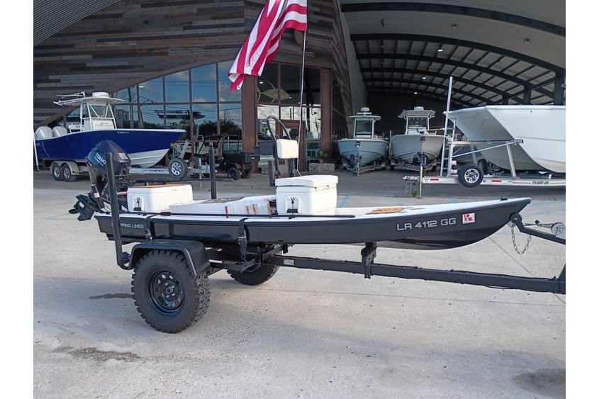 2013 Pelican Ambush boat on trailer with American flag, parked near a boat storage facility.