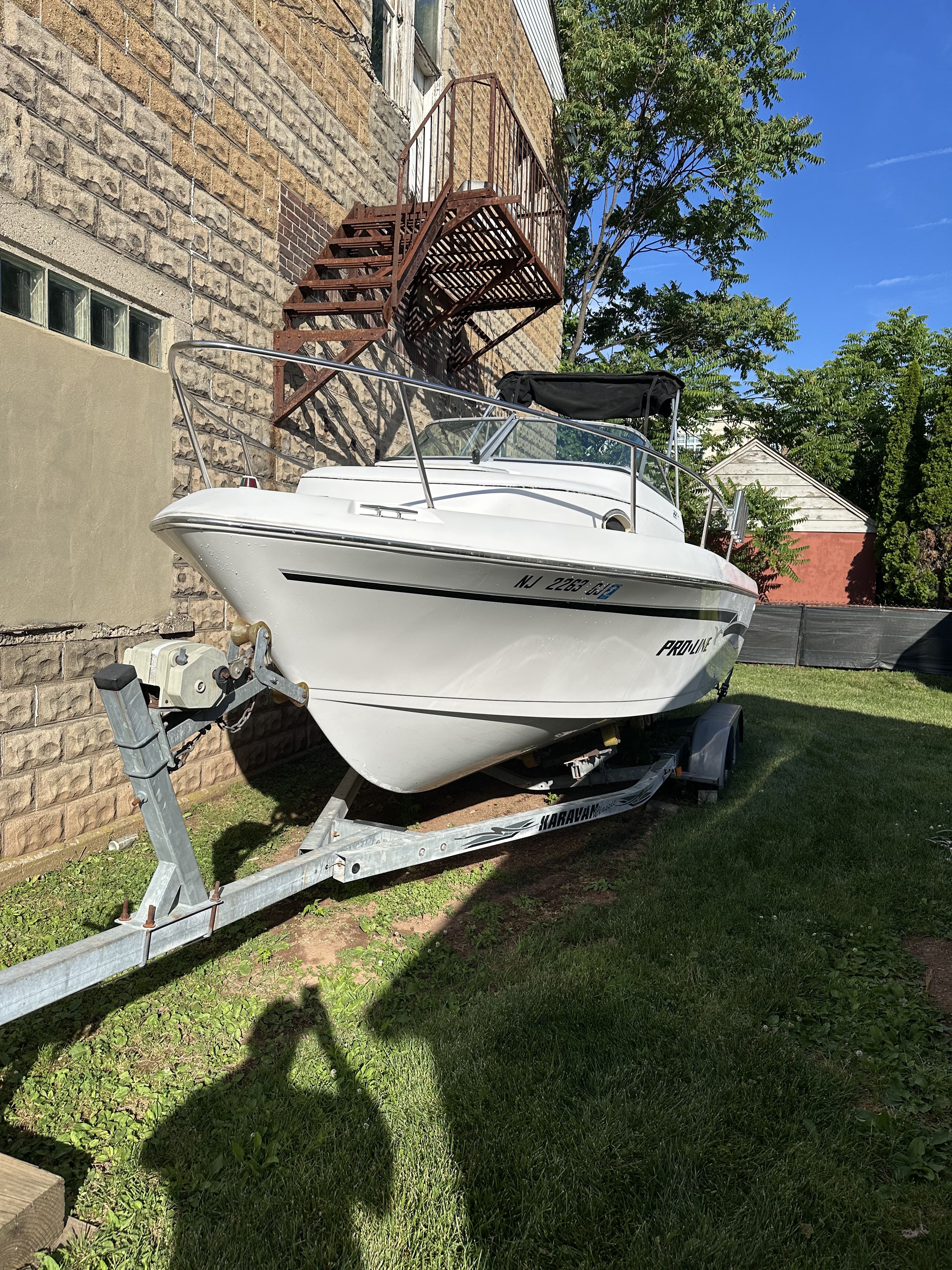 A white boat on a trailer beside a building.