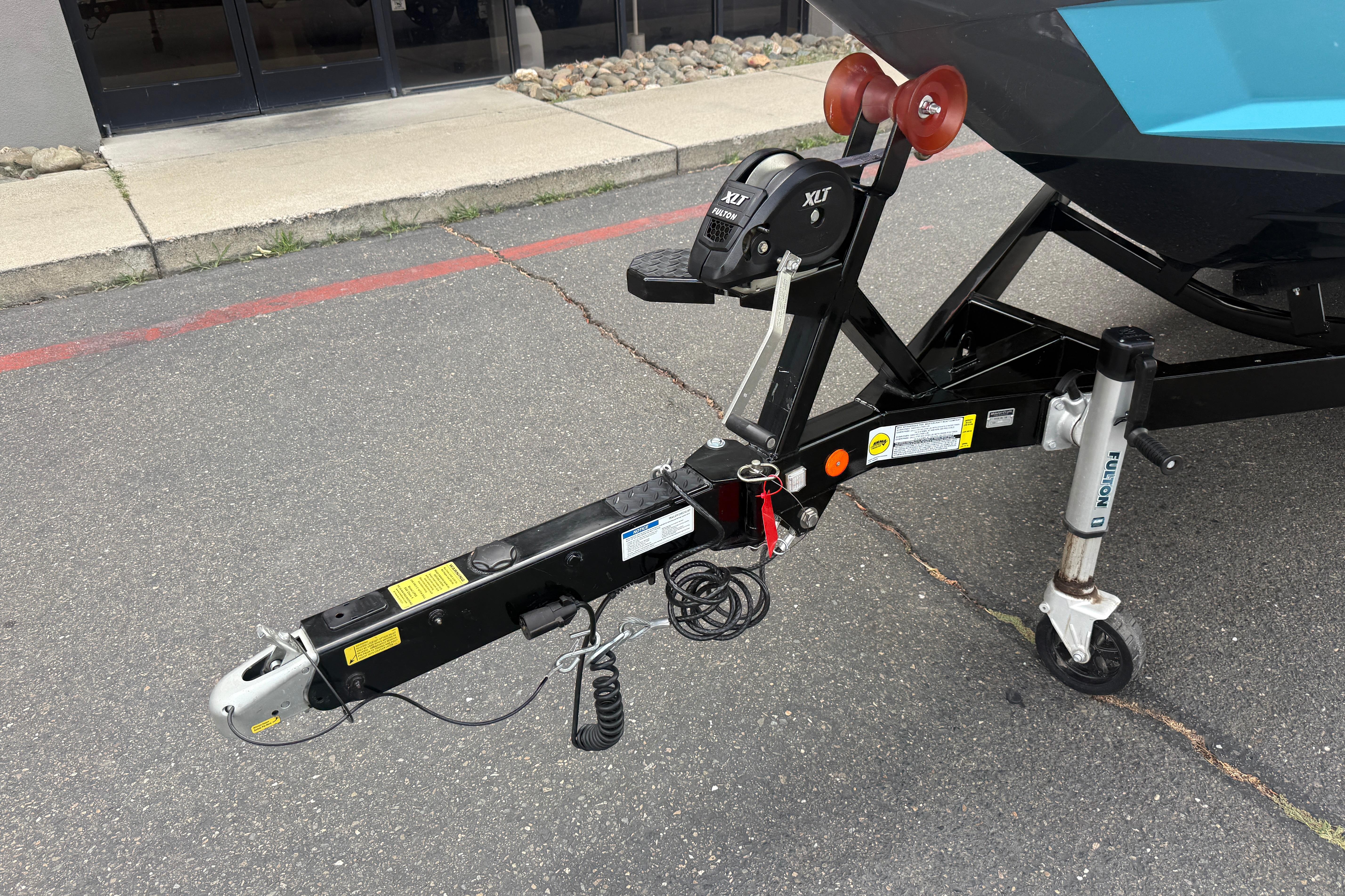Trailer hitch of a 2018 MasterCraft XT21 boat on pavement.