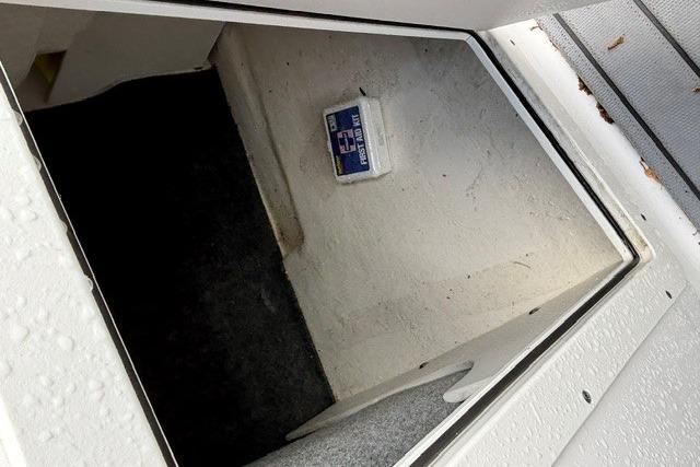 Storage compartment in a 2021 Chaparral 21 SSi boat, featuring carpeted interior.