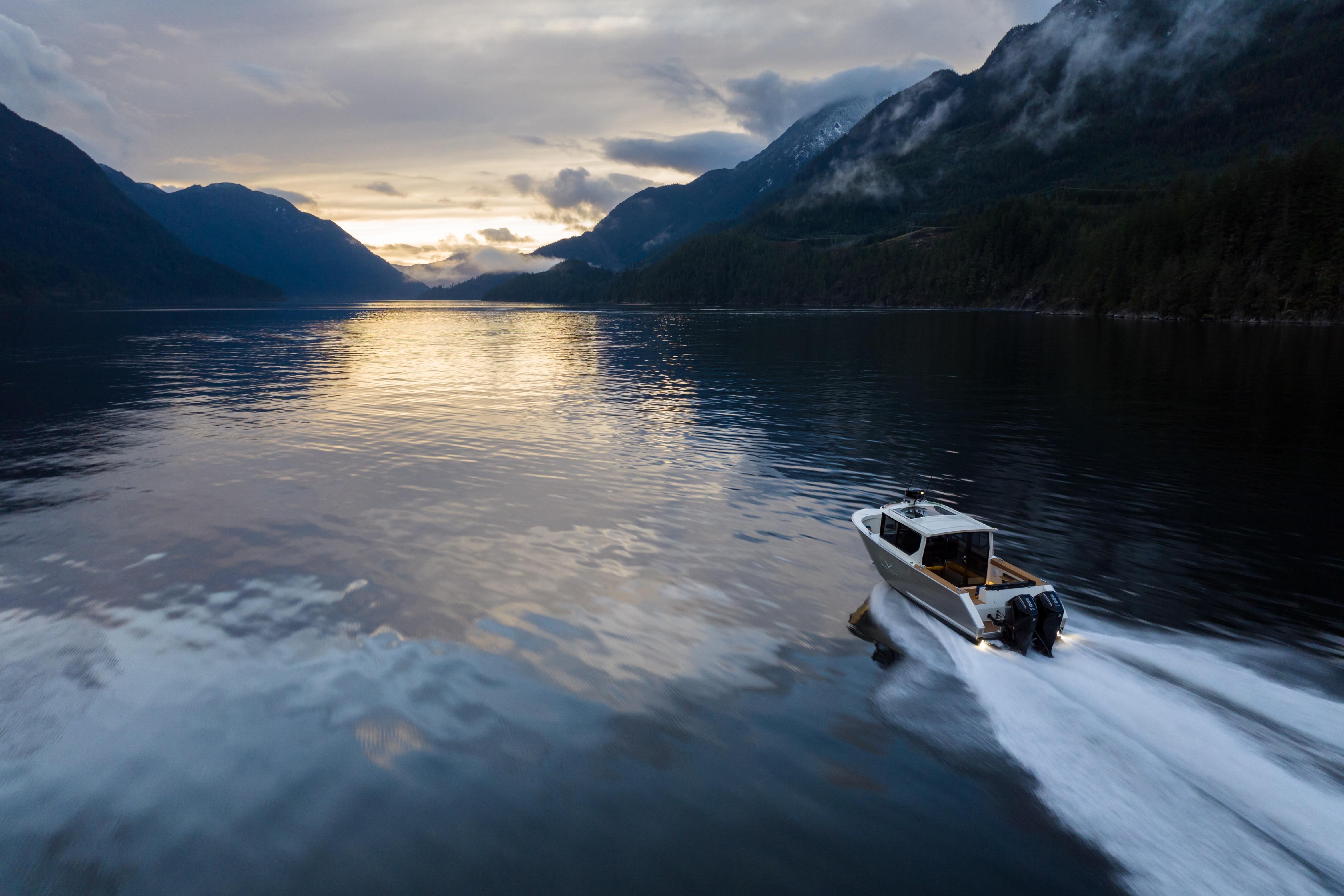 2026 Jasper Marine Defender 22 cruising on a serene lake at sunset, surrounded by mountains.