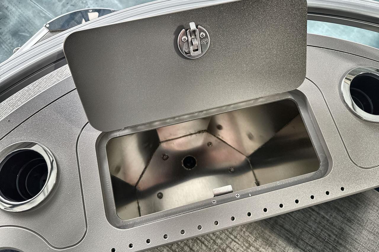 Open storage compartment on 2026 Landau Island Breeze 23F boat dashboard with cup holders.