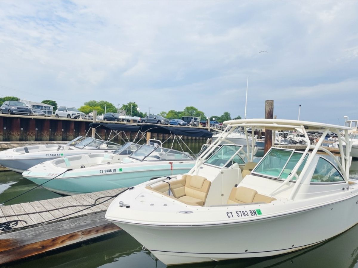 Three boats are docked in the water. The front boat is a white Sailfish 245 DC.