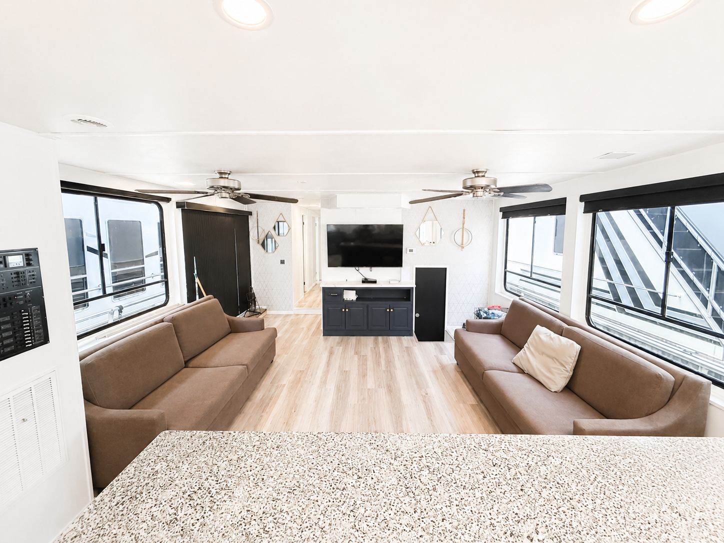 Interior of a houseboat with sofas, TV, and modern decor.