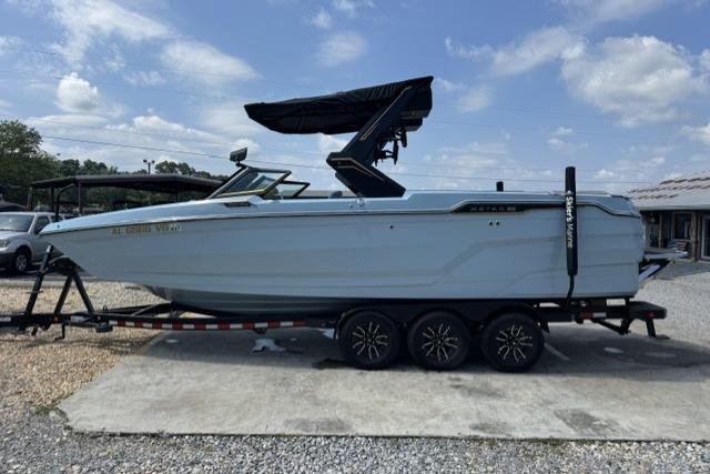 2026 MasterCraft XStar 25 boat on trailer, side view, under clear blue sky.