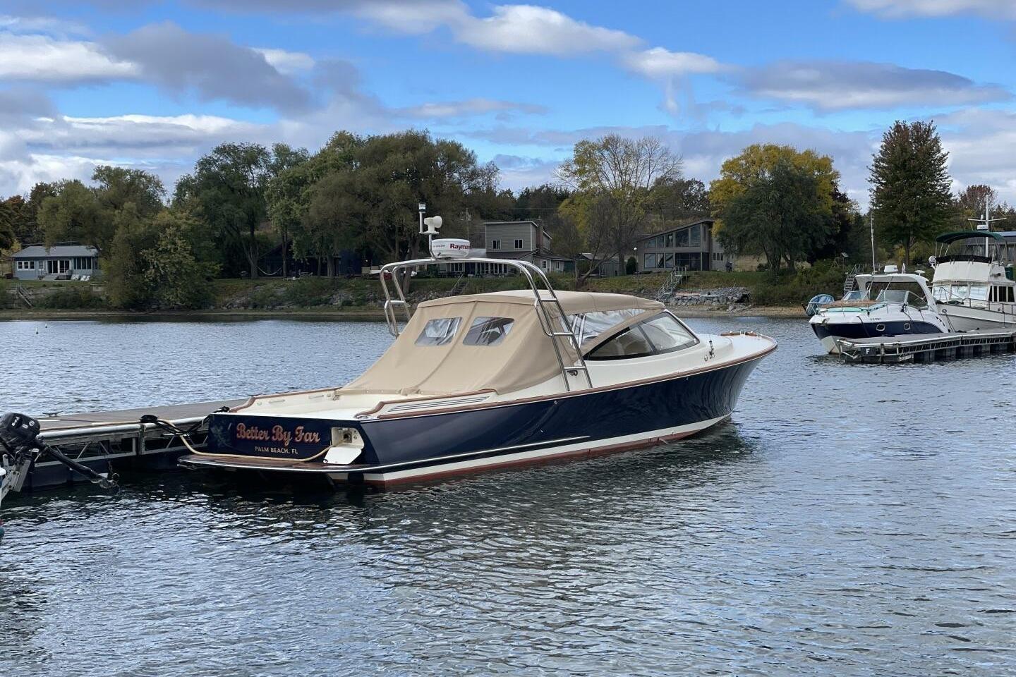 2012 Hinckley Runabout 38 docked on a serene lake with trees in the background.