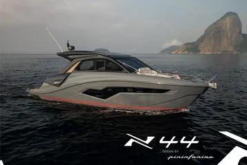 2025 NX Boats NX44 PININFARINA yacht cruising on serene waters with scenic coastal backdrop.