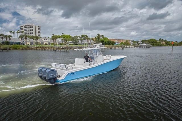 2015 Invincible 36 boat cruising on a calm river under cloudy skies.