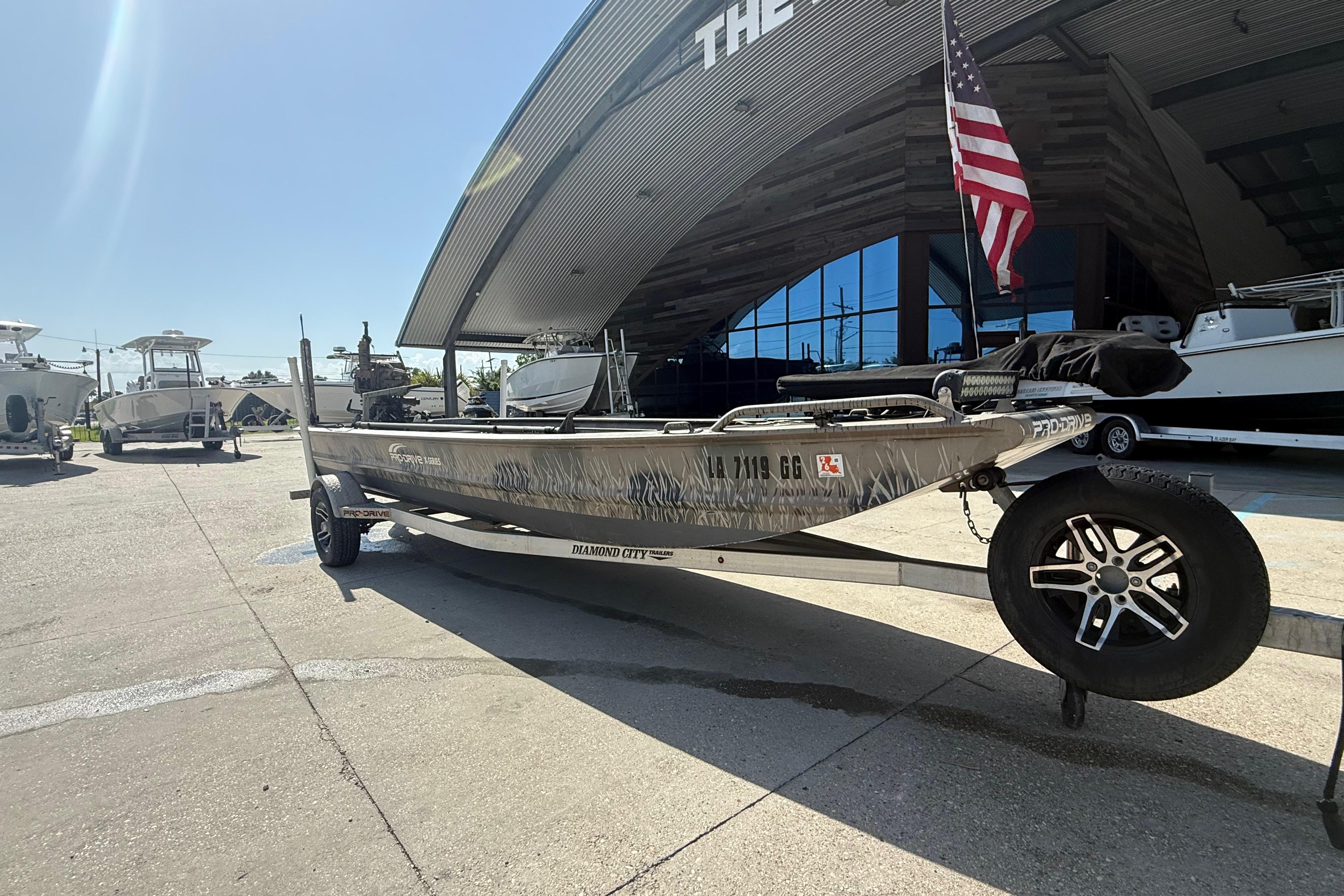 2017 Pro-Drive 2048 boat on trailer, parked outside a showroom with an American flag.