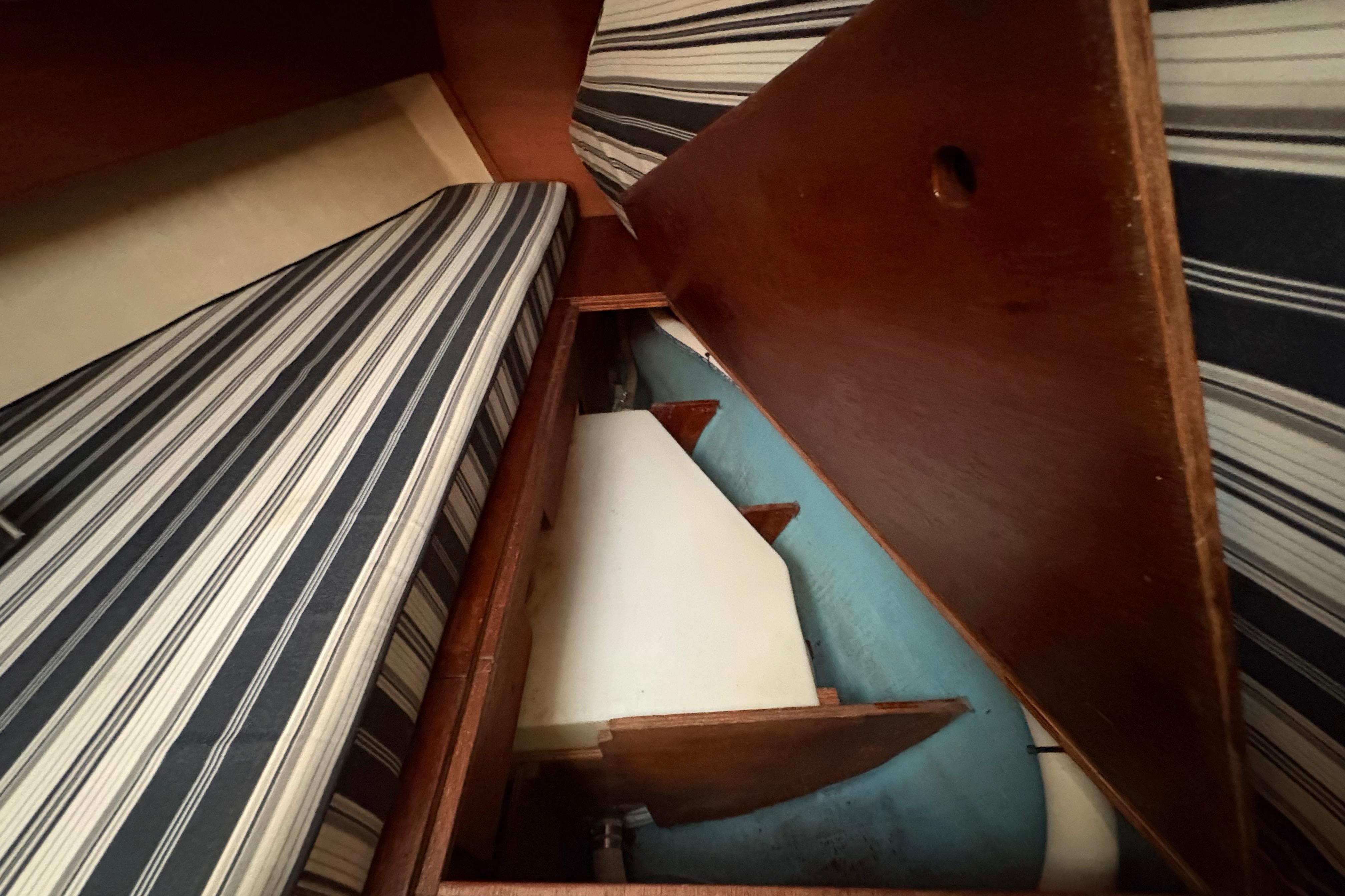 Interior of 1981 Sabre 31 sailboat with striped cushions and wooden storage compartment.
