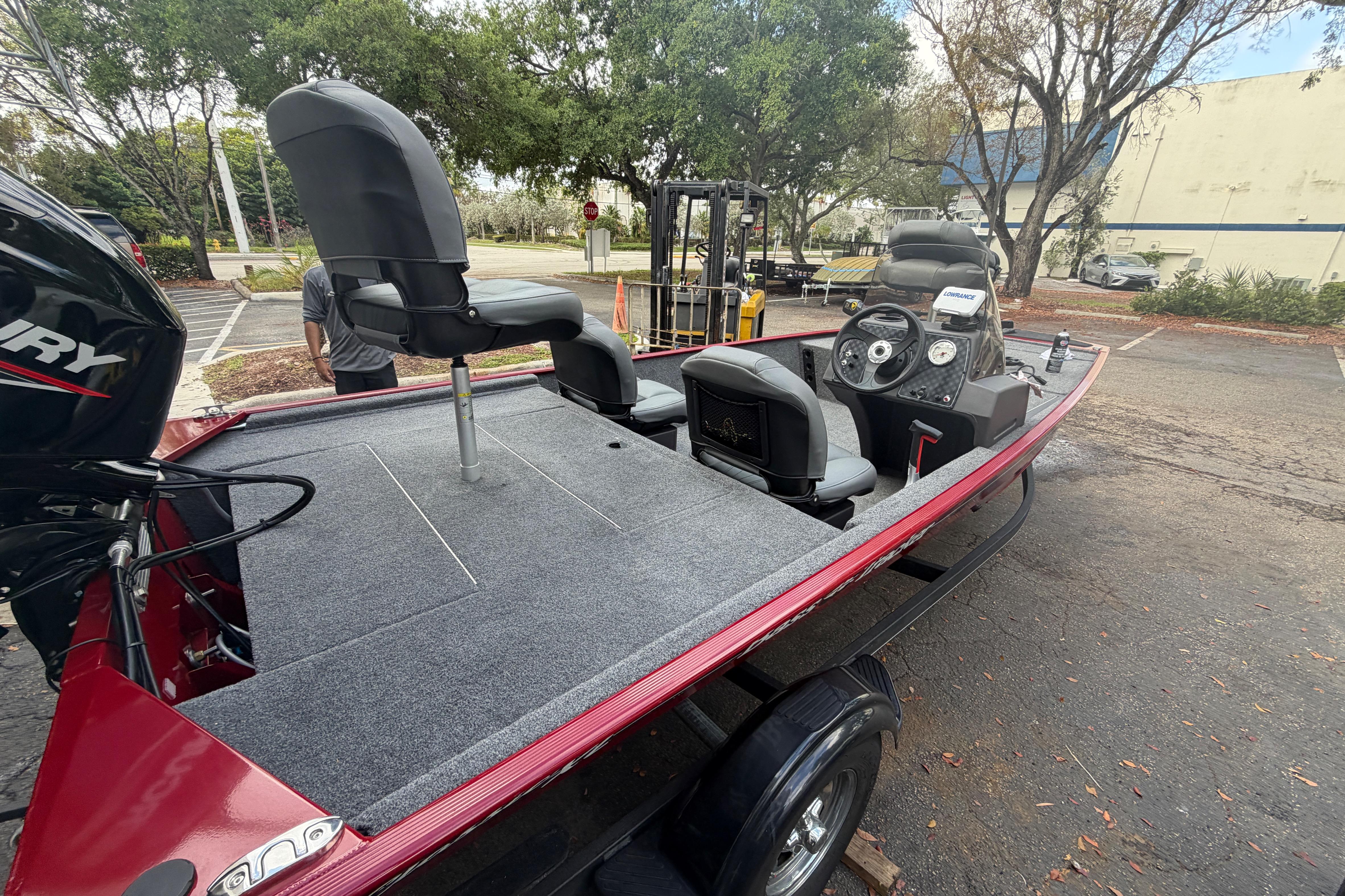 2023 Bass Tracker III Classic fishing boat with seating and control panel in a parking area.