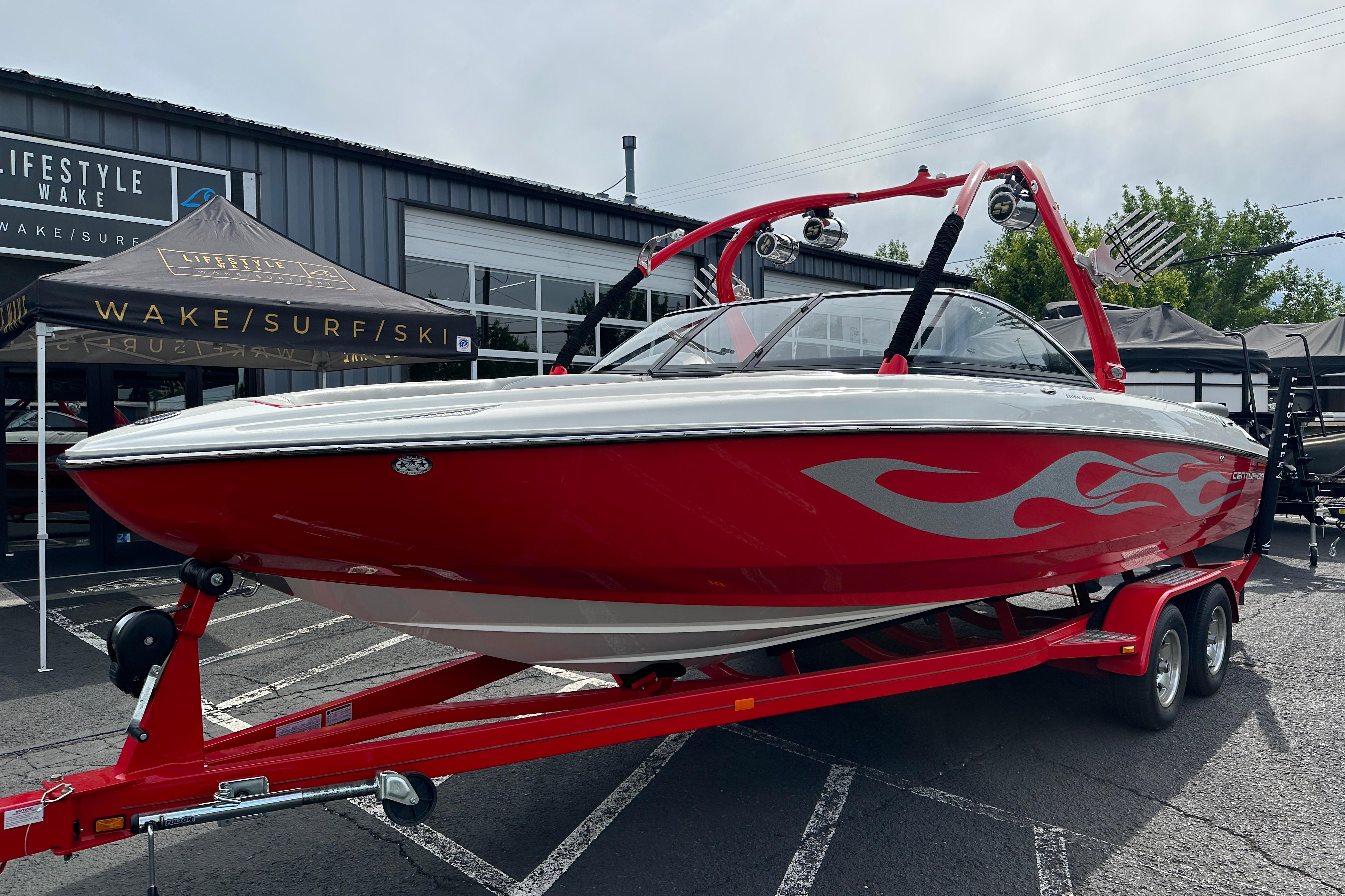 2008 Centurion Enzo SV240 boat with red flame design on trailer at dealership.