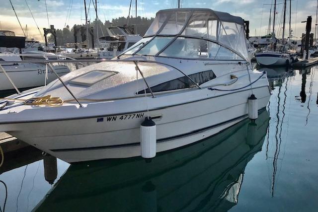 1998 Bayliner 2655 Ciera Sunbridge docked in a marina, surrounded by other boats.