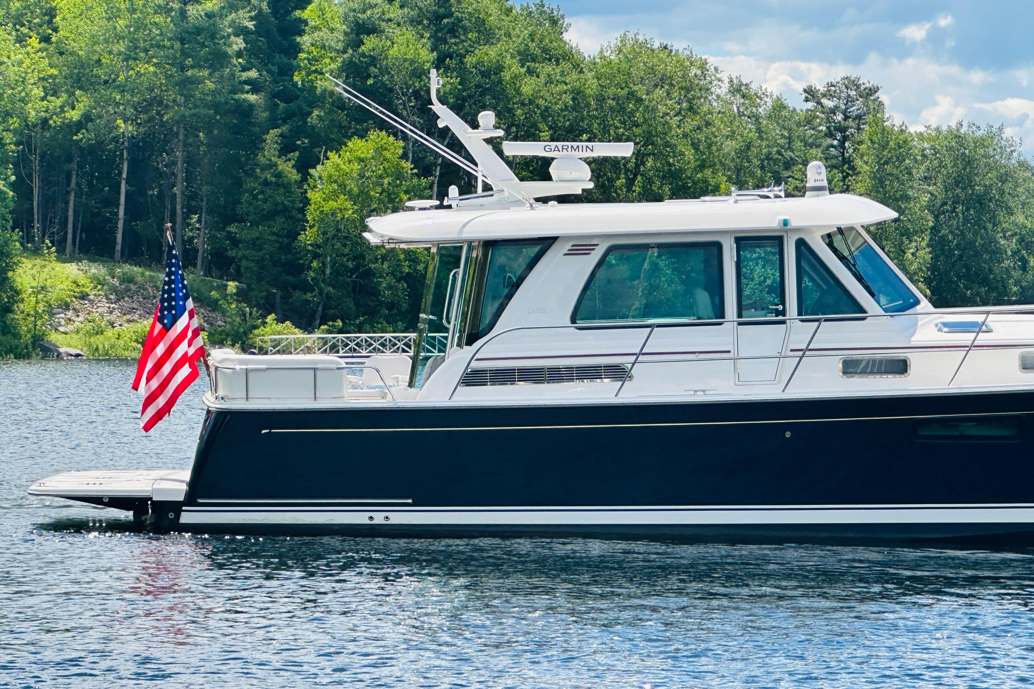 2025 Sabre 48 Salon Express yacht on a serene lake with lush forest backdrop.