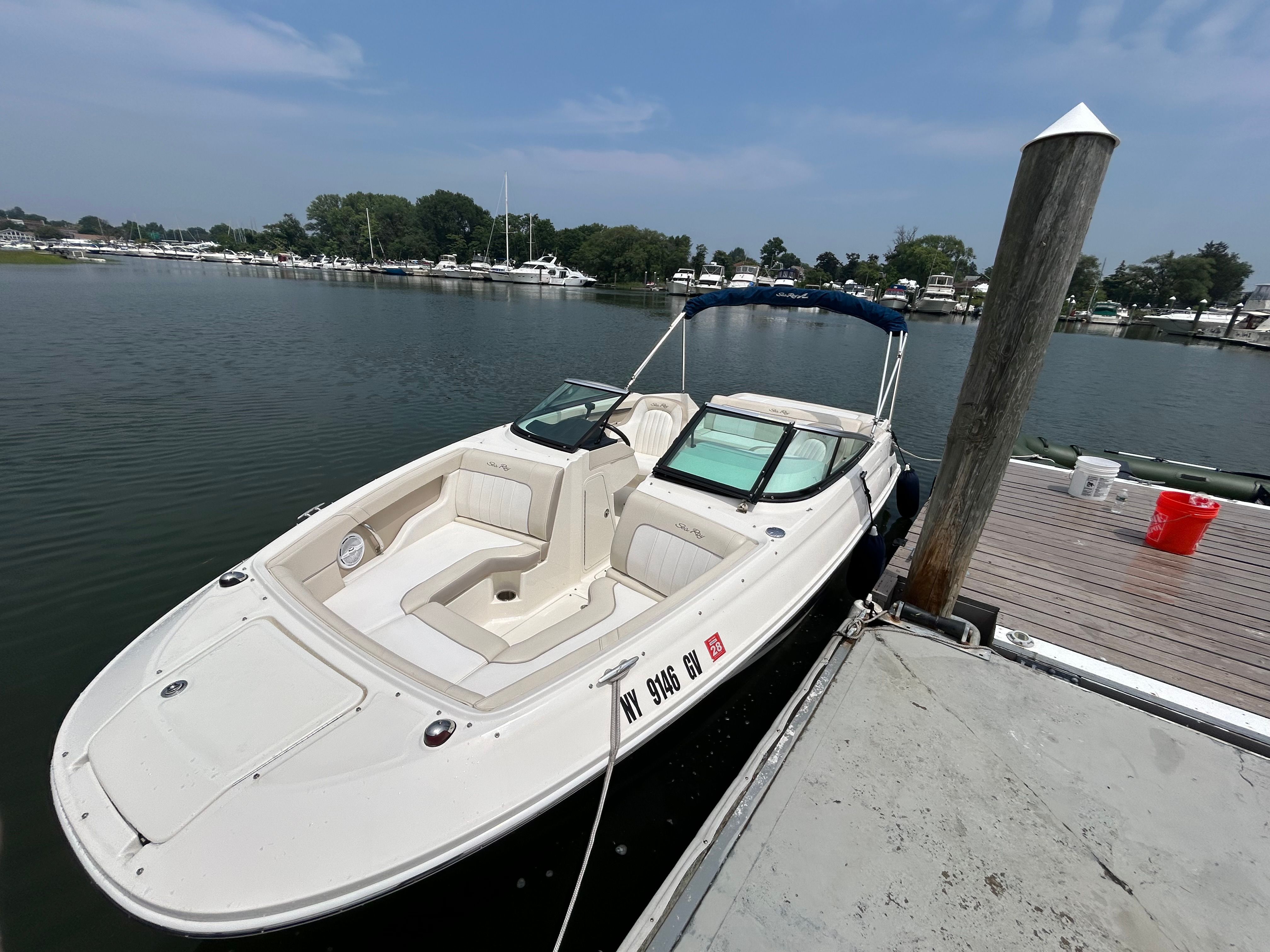 A white motorboat docked at a pier in a calm harbor.