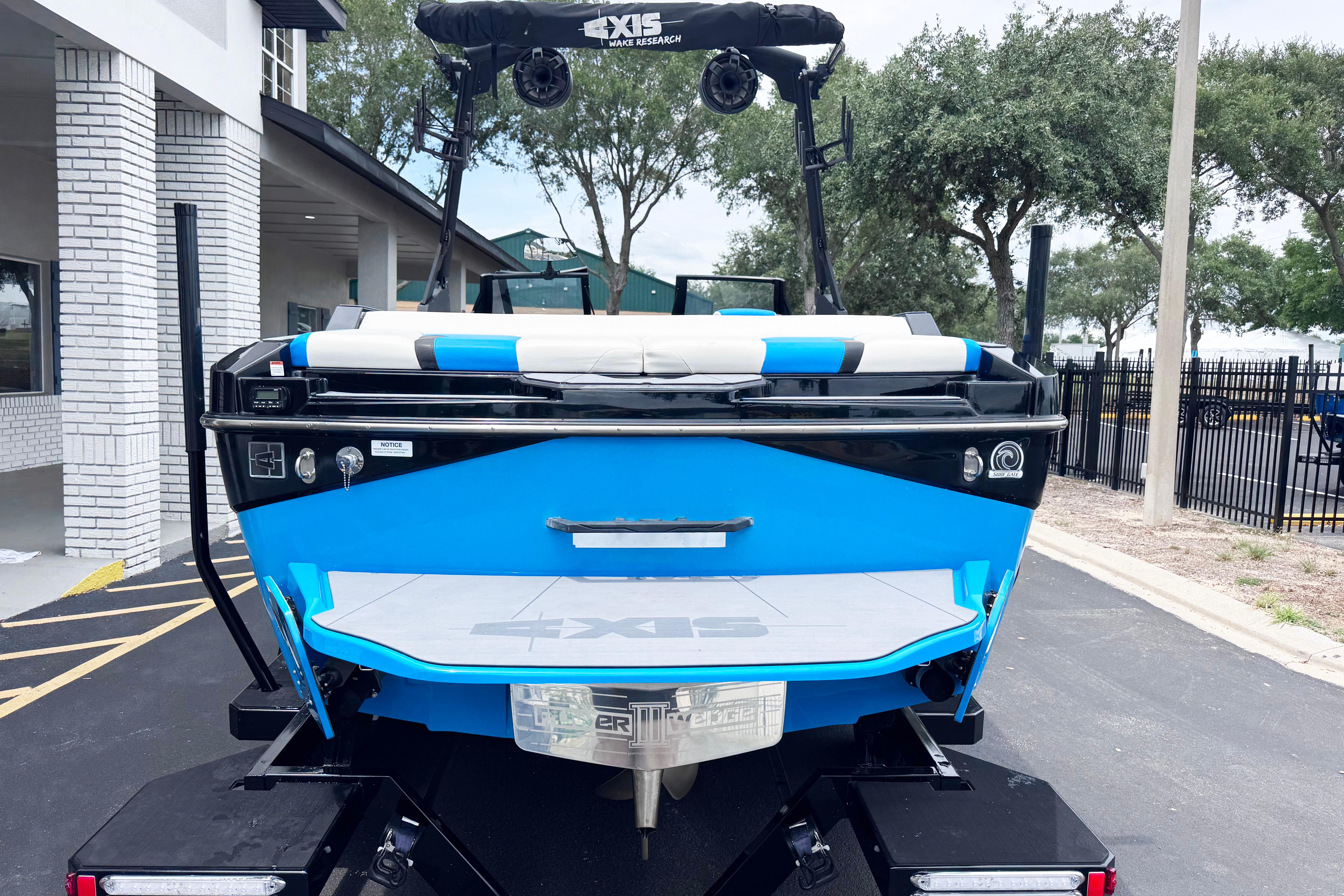 2022 Axis T220 boat in vibrant blue, parked outdoors near a building.